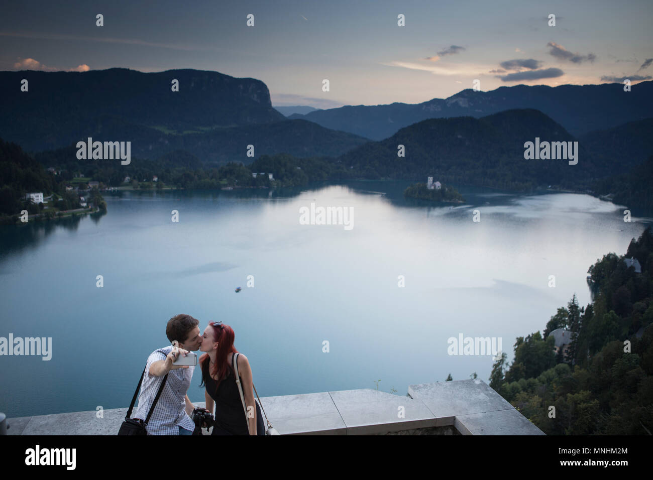 Pareja joven de Eslovenia es besar teniendo selfie encima de lago de Bled, Eslovenia Triglav Foto de stock