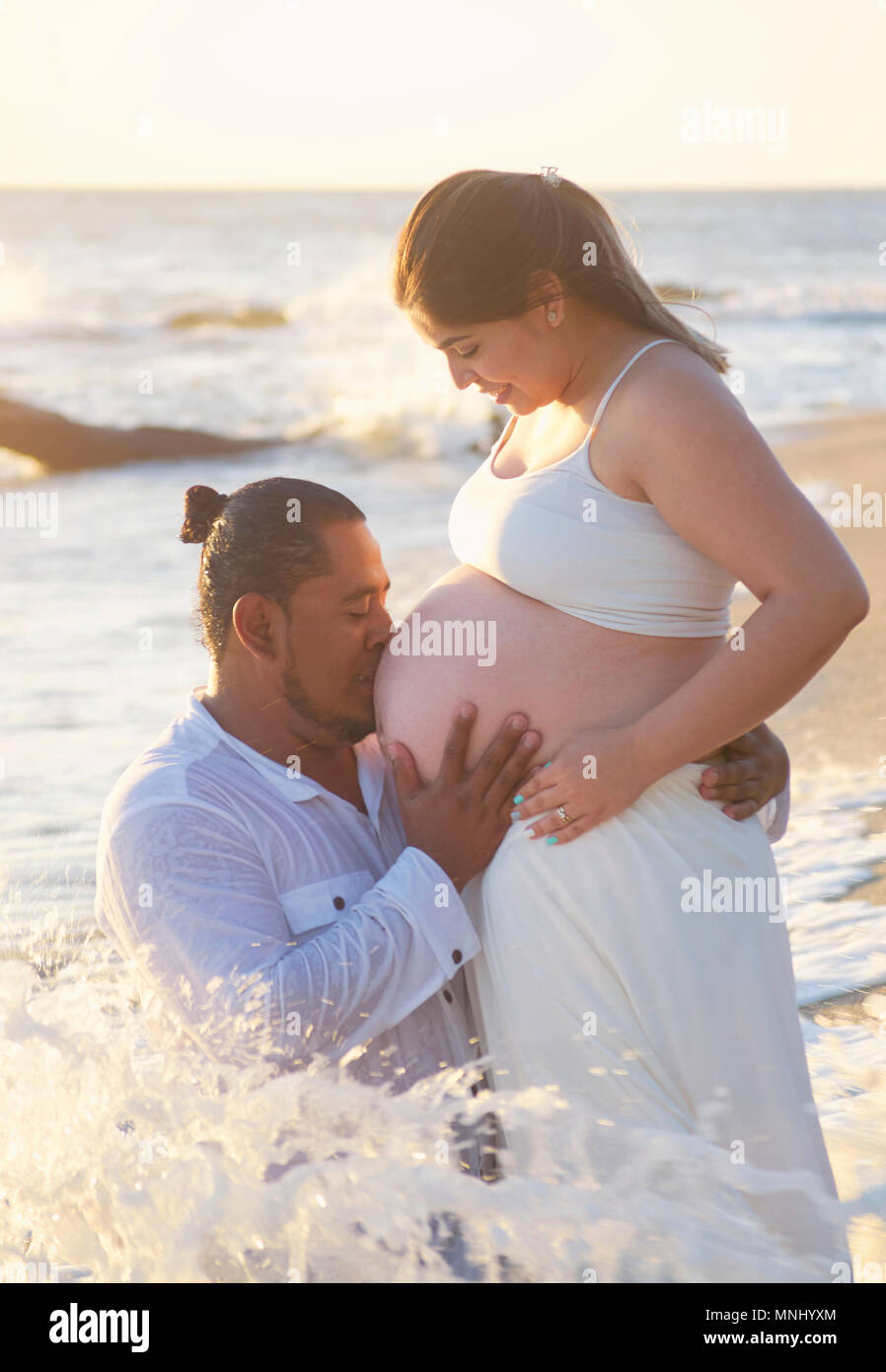 Feliz pareja de hispanos en la playa. Hombre bese embarazada vientre  Fotografía de stock - Alamy