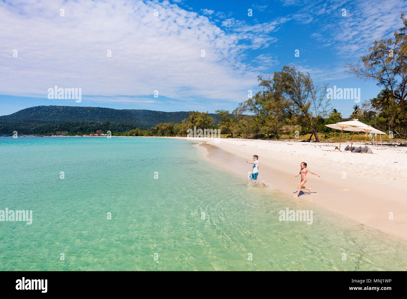 Los niños se diviertan en tropical beach durante las vacaciones de verano jugando juntos en aguas someras Foto de stock