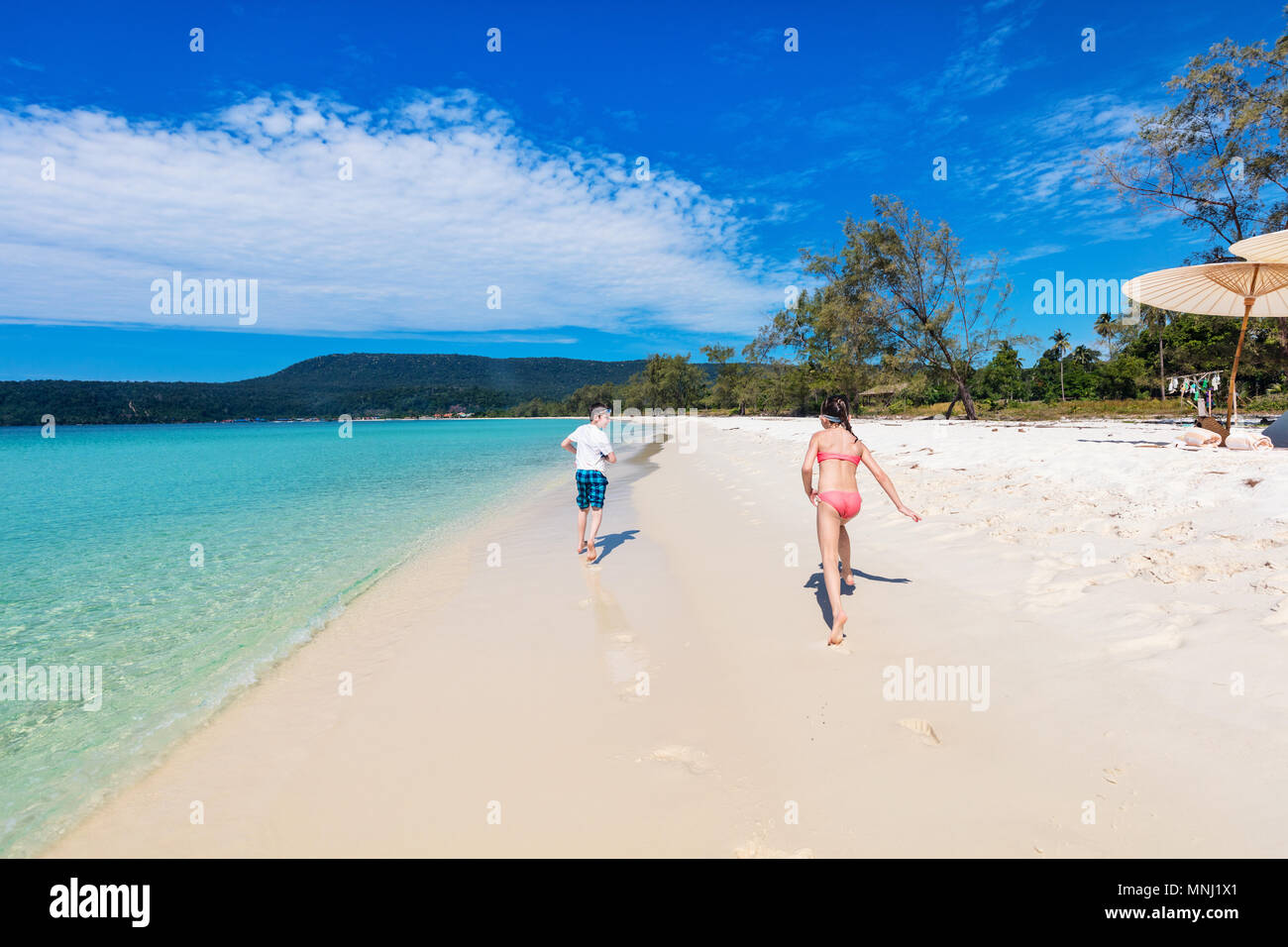 Los niños se diviertan en tropical beach durante las vacaciones de verano jugando juntos en aguas someras Foto de stock
