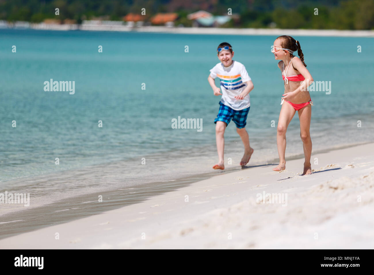 Los niños se diviertan en tropical beach durante las vacaciones de verano jugando juntos en aguas someras Foto de stock