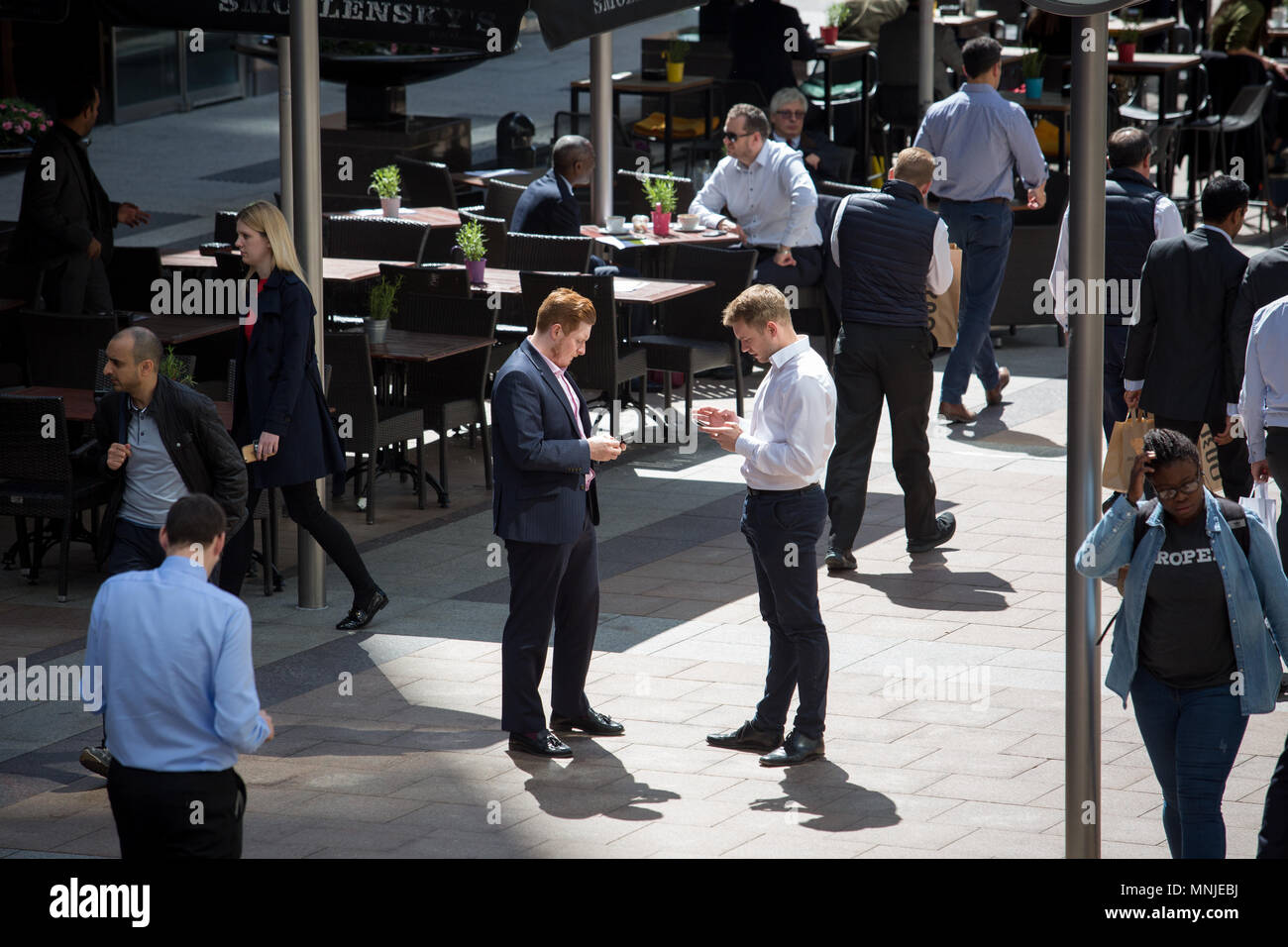 Dos trabajadores de la ciudad juntos mirando sus teléfonos Foto de stock