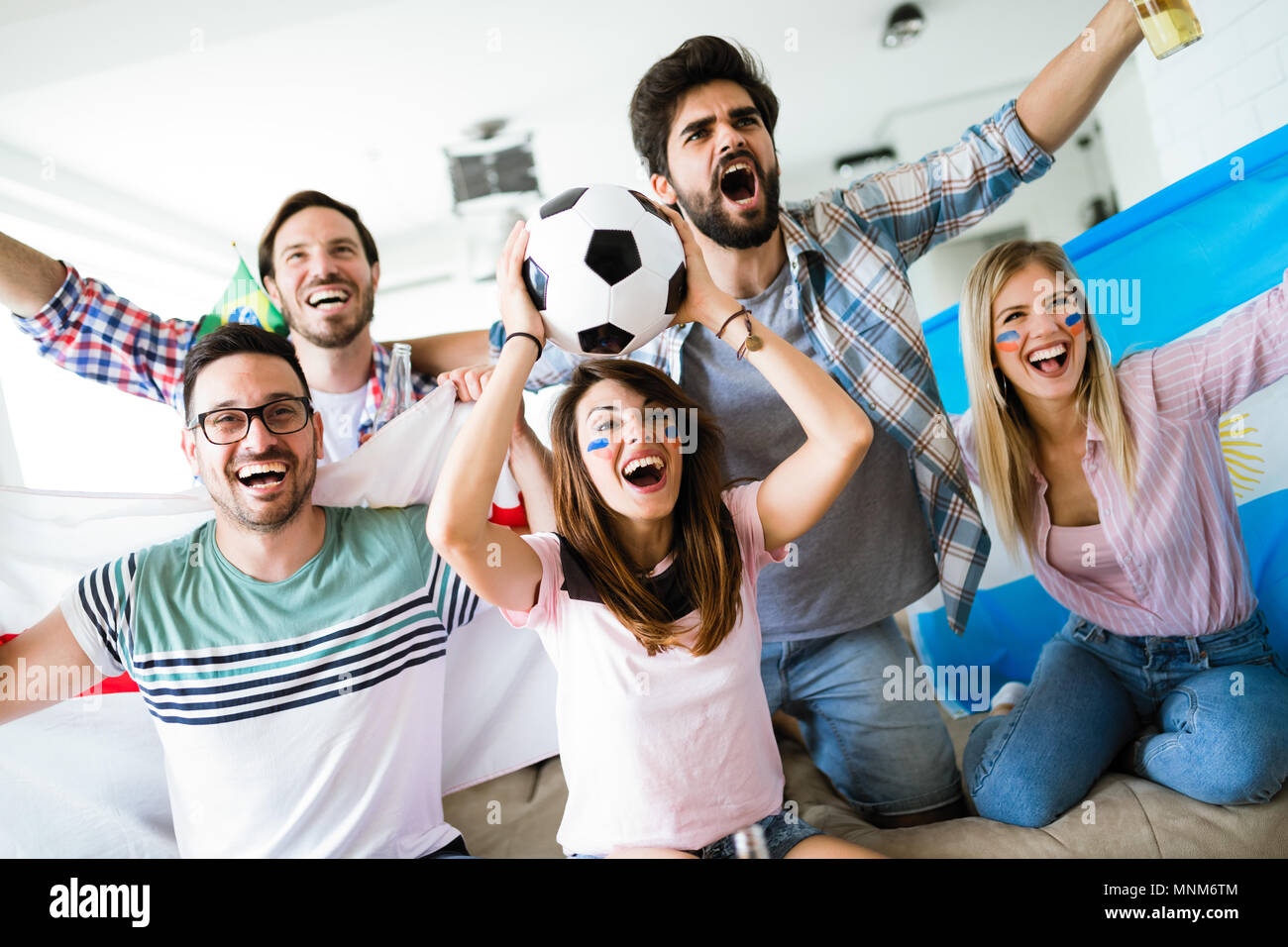 Alegre grupo de amigos viendo partido de fútbol en la televisión. Foto de stock