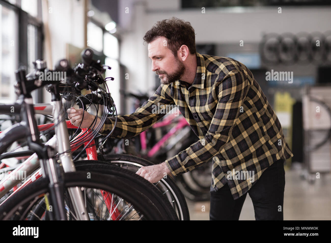 Macho adulto elegir una bicicleta en una tienda de ciclo Foto de stock