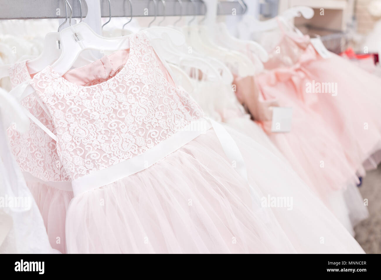 Muchos boda flor niña vestidos de fiesta en la boutique tienda de descuento, rosa de prendas colgadas en perchas rack closeup fila con encajes, tul blanco, diseño Fotografía de stock - Alamy Muchos boda flor niña vestidos de fiesta en la boutique tienda de descuento, rosa de prendas colgadas en perchas rack closeup fila con encajes, tul blanco, diseño Fotografía de stock - Alamy