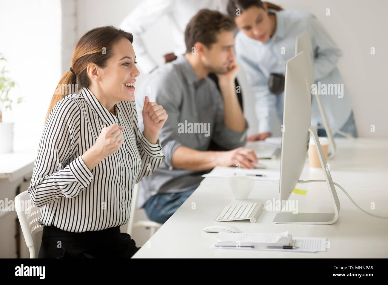 La empresaria emocional mirando el monitor de escritorio vítores espere Foto de stock