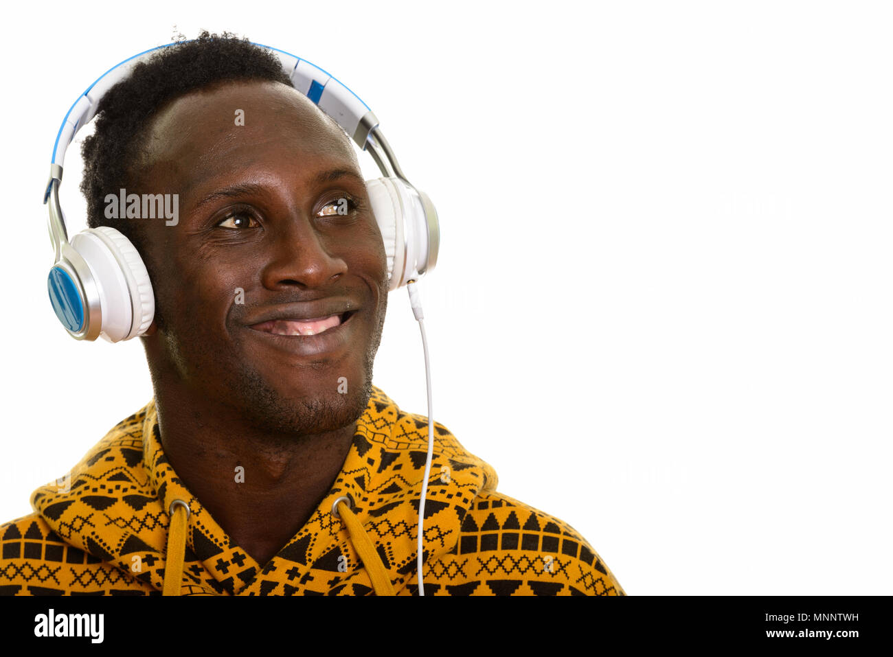 Joven hombre africano negro feliz y sonriente escuchando música whi Foto de stock