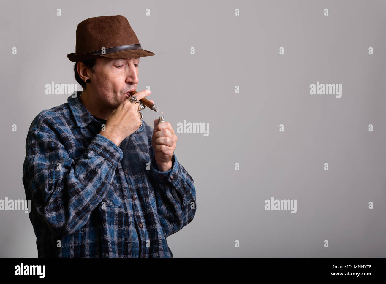 Foto de estudio de gángster maduro hombre mientras que fumar cigarros de iluminación Foto de stock