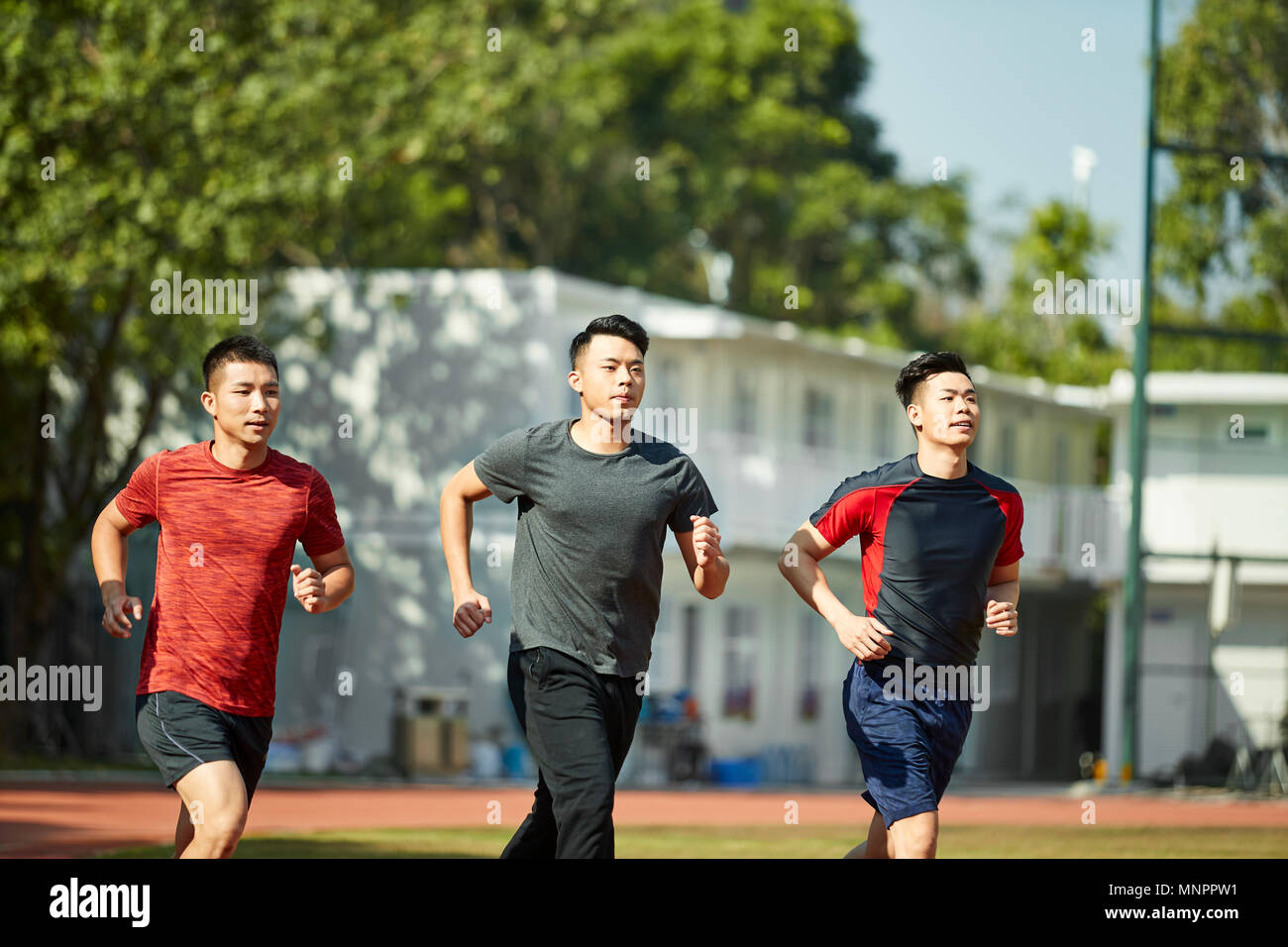 Tres adultos jóvenes asiáticos ENTRENAMIENTO RUNNING en la vía Foto de stock