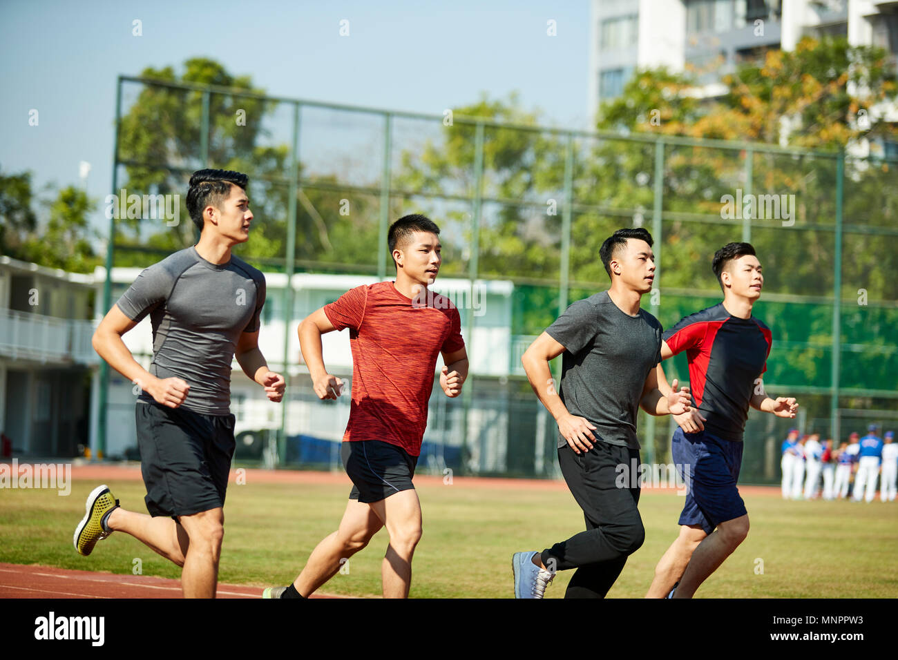Cuatro adultos jóvenes asiáticos ENTRENAMIENTO RUNNING en la vía. Foto de stock