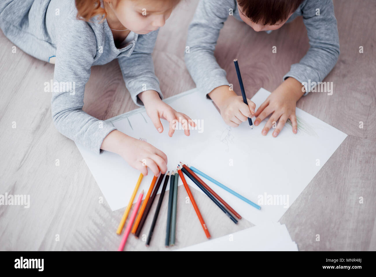 Los niños acostarse en el suelo, en pijama y dibujar con lápices. Lindo niño pintura de lápices Foto de stock