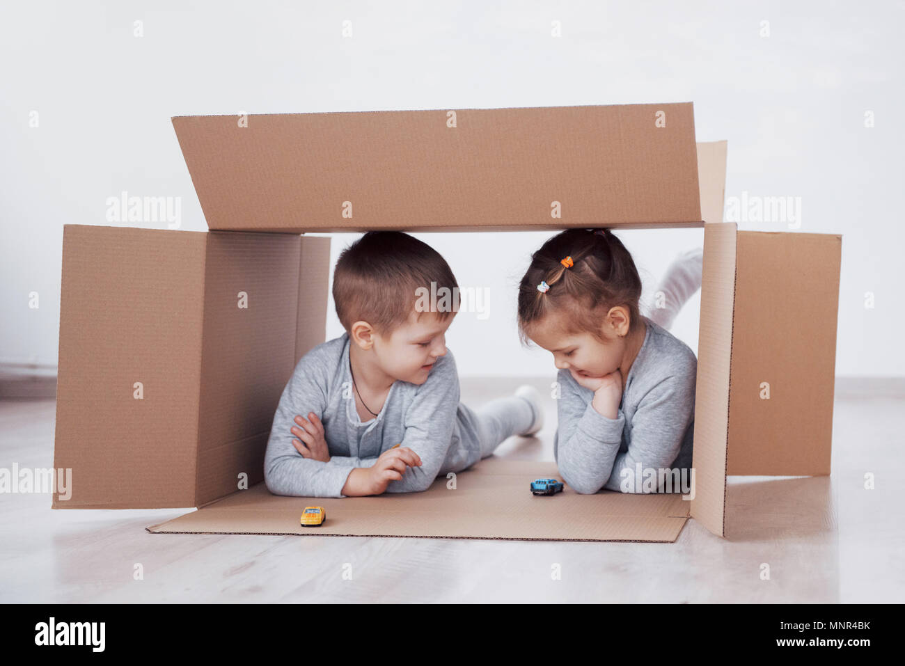 Dos niños pequeños un chico y chica se acaba de mudarse a una nueva casa. Concepto foto .. Los niños se divierten. Foto de stock