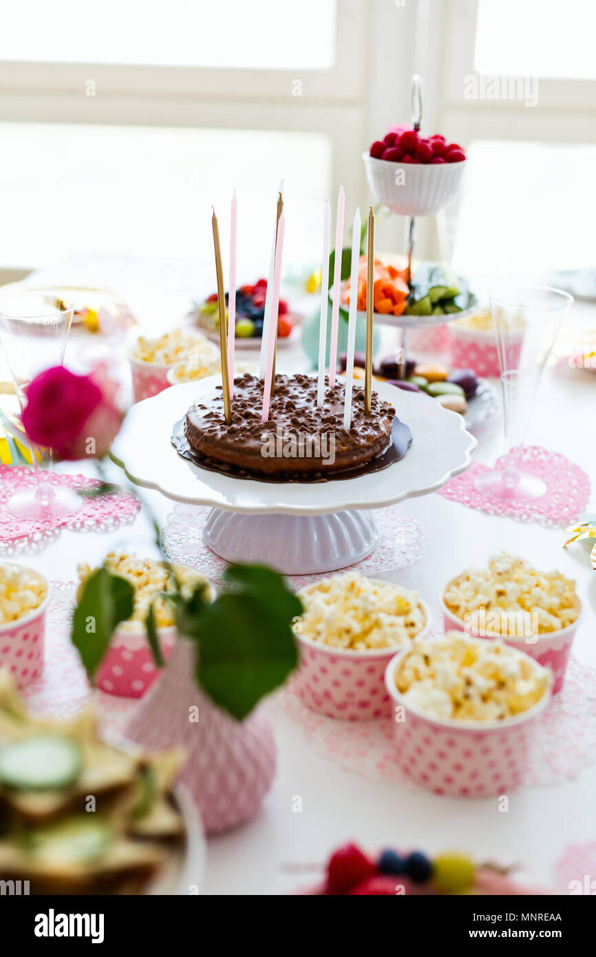 Torta, caramelos, malvaviscos, palomitas de maíz, frutas y otros dulces de postre mesa en la fiesta de cumpleaños para niños Foto de stock