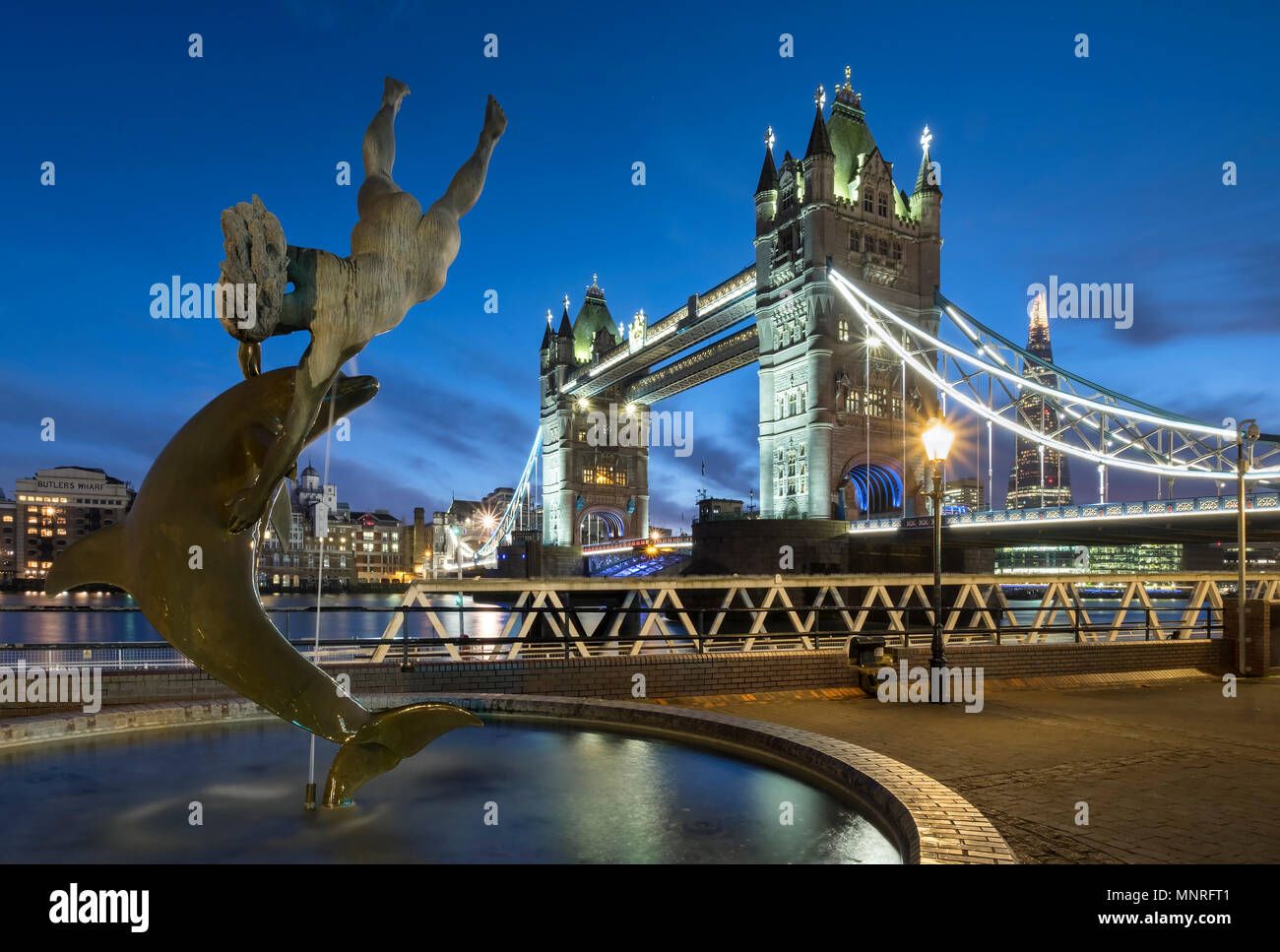 Chica con una fuente del delfín, el Tower Bridge y el fragmento de noche, Londres, Inglaterra, Reino Unido. Foto de stock