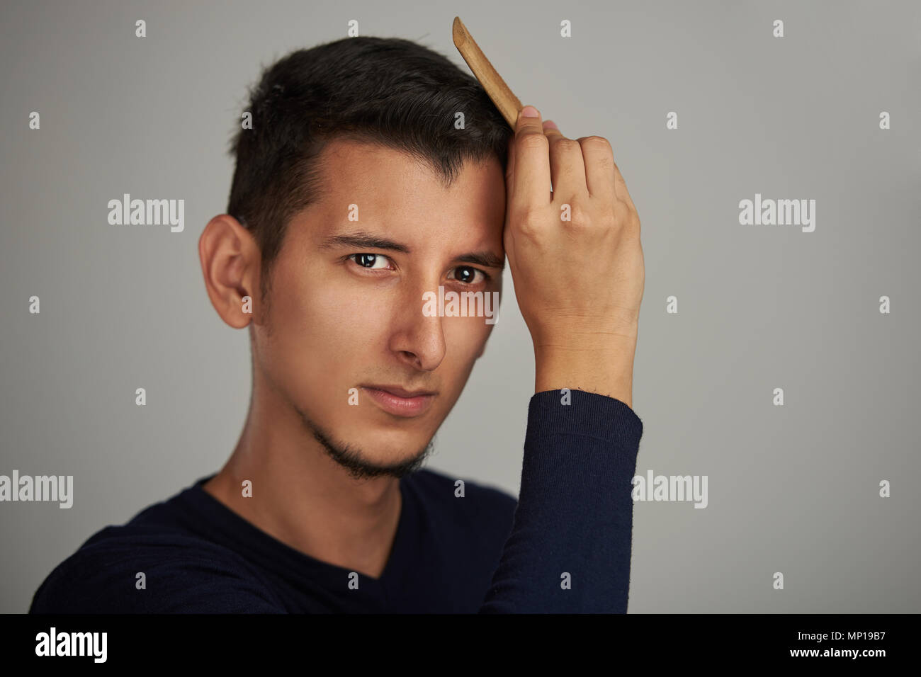 Guapa joven hombre hispano de arreglar su cabello Foto de stock