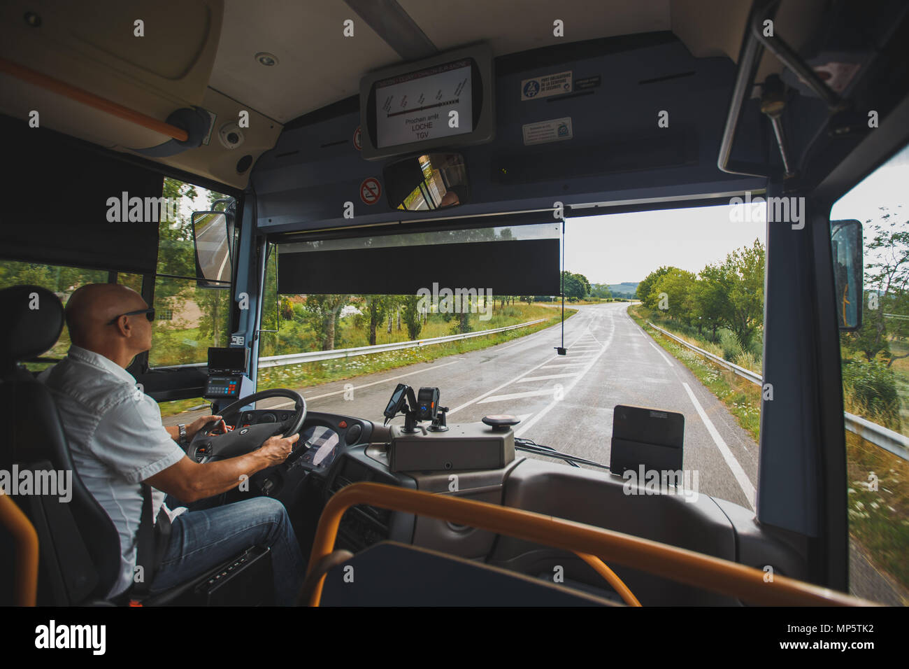 El tema es la profesión de conductor y transporte de pasajeros. Un hombre en gafas de sol un conductor acciona un autobús regional turística en la región de Francia Foto de stock