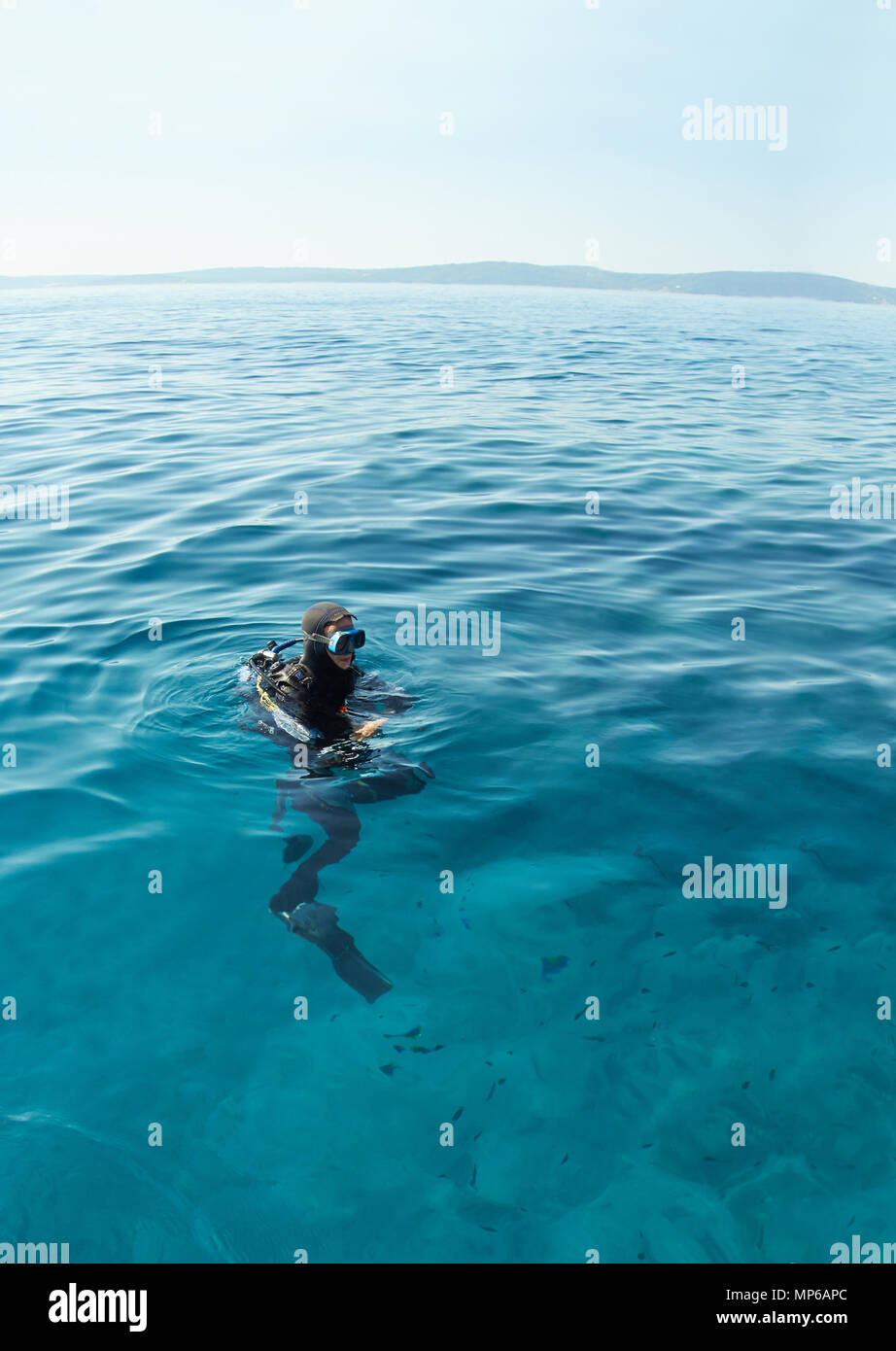 Scuba Diver en la superficie del mar Adriático en Croacia. Long shot. Horizonte sobre el agua. Foto de stock