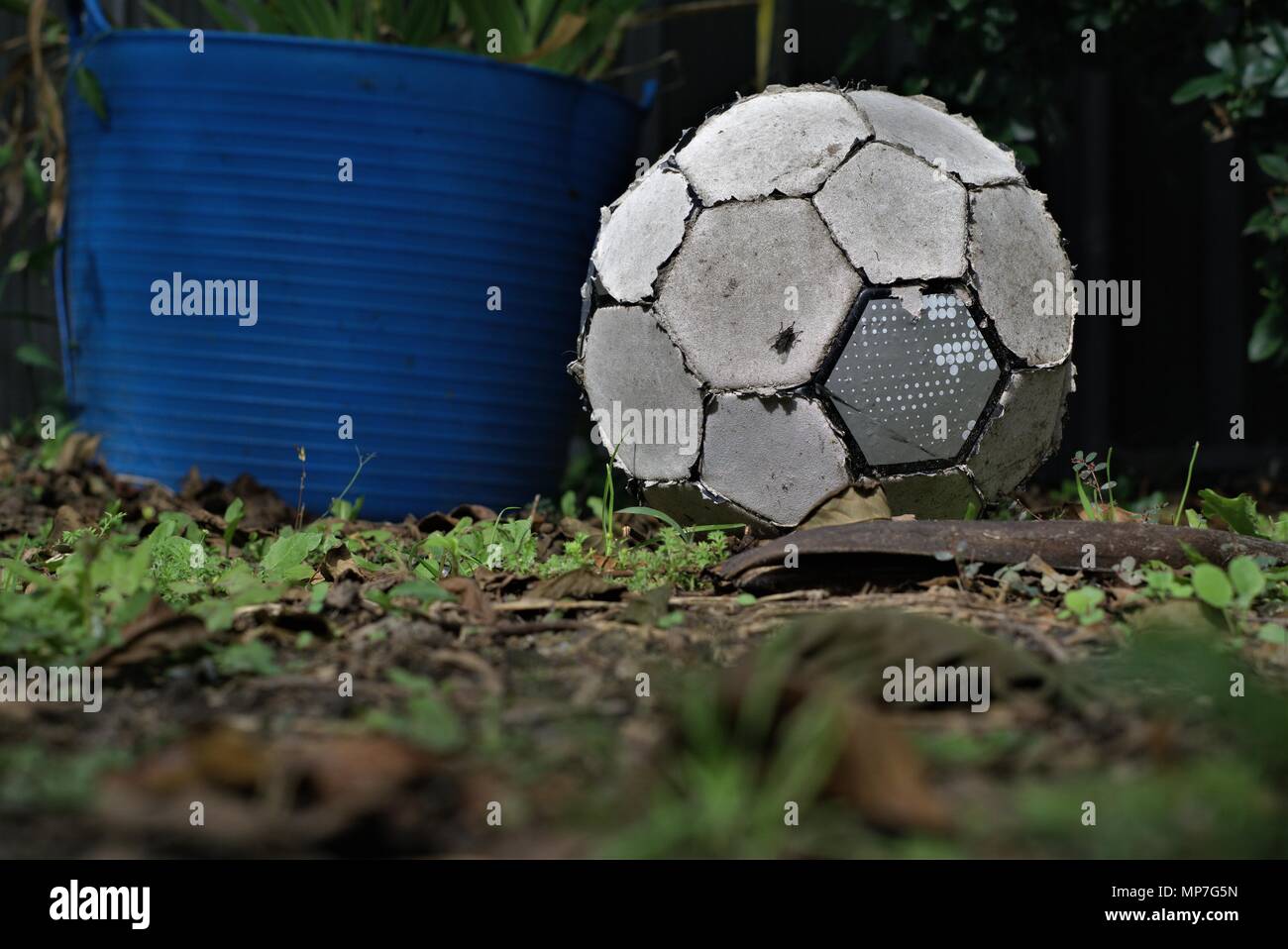 Roto viejo balón de fútbol sentar sobre el césped. Fútbol desgastados. Concepto de persona inactiva o inútil objeto. Foto de stock