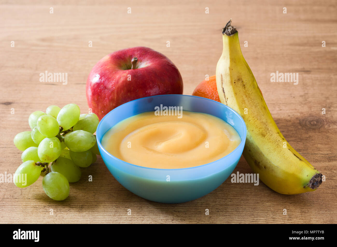 Comida para bebés: colorido plato de puré de frutas sobre la mesa de madera Foto de stock