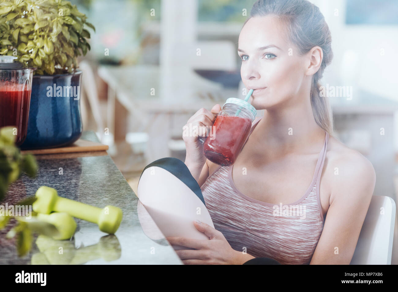 En Sportswoman detox dieta depurativa tomando cuerpo sano cóctel rojo después de gimnasia Foto de stock