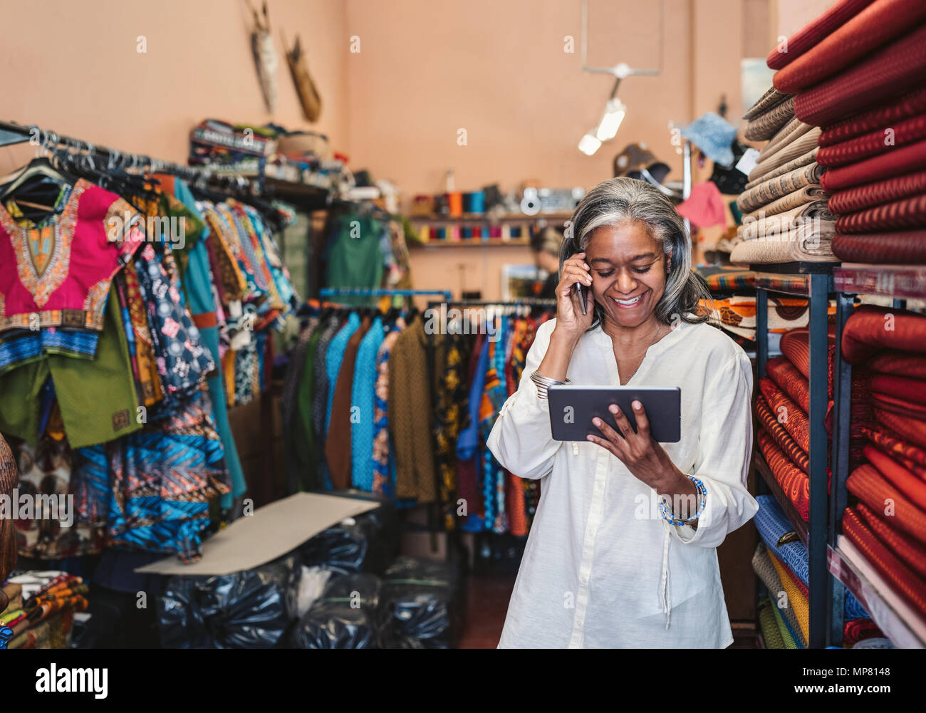 Mujer sonriente hablando por un teléfono en su tienda de tela Foto de stock