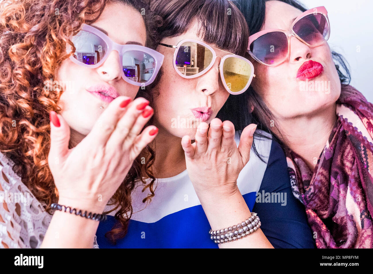 Tres jóvenes caucásicos gracioso loca hacer una fiesta con coloridas gafas de sol. Enviar un beso y divertirse juntos en una amistad real de un grupo de personas. Foto de stock