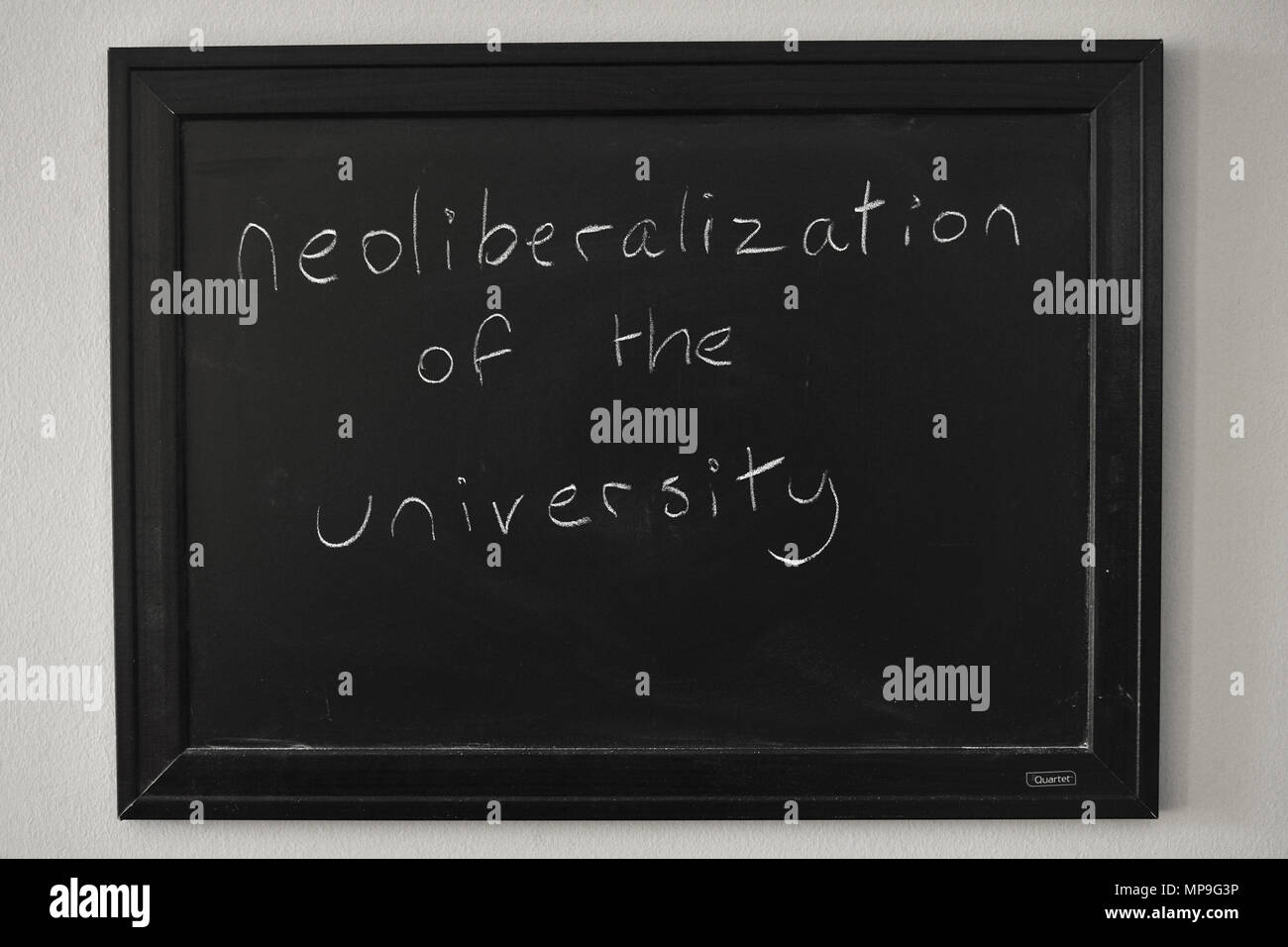 Neoliberalismo de la universidad escritas en blanco tiza en una pizarra en la pared. Foto de stock