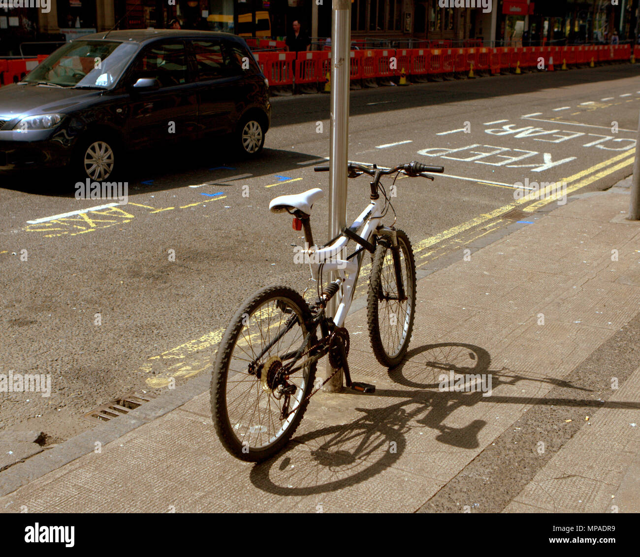 Sombra de una bicicleta junto a la concurrida calle con coche con líneas amarillas y mantener marcas claras de Sauchiehall Street, Glasgow, Reino Unido Foto de stock