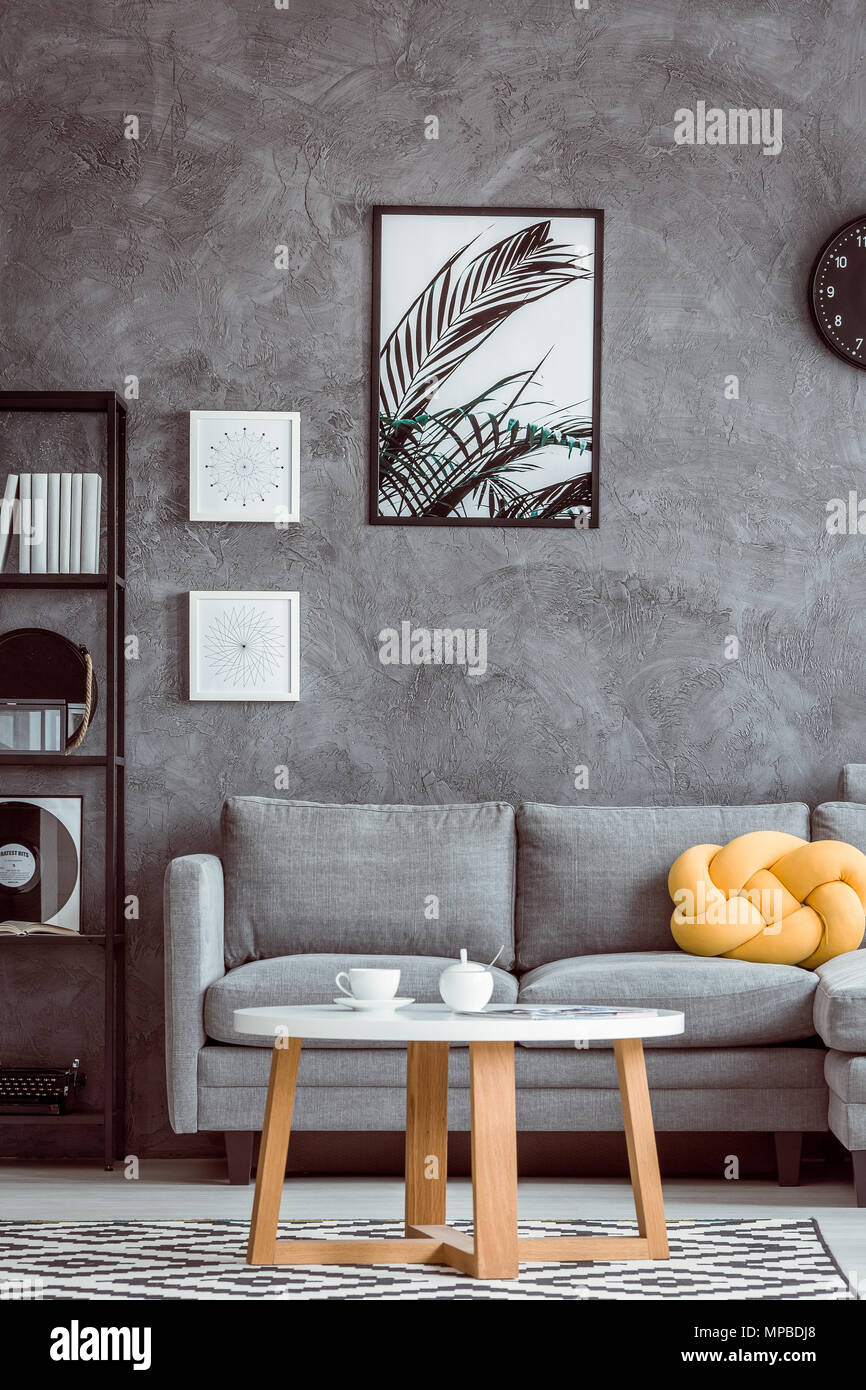Pintura de las hojas en la pared gris oscuro arriba sofá con almohada  amarilla en simple salón Fotografía de stock - Alamy