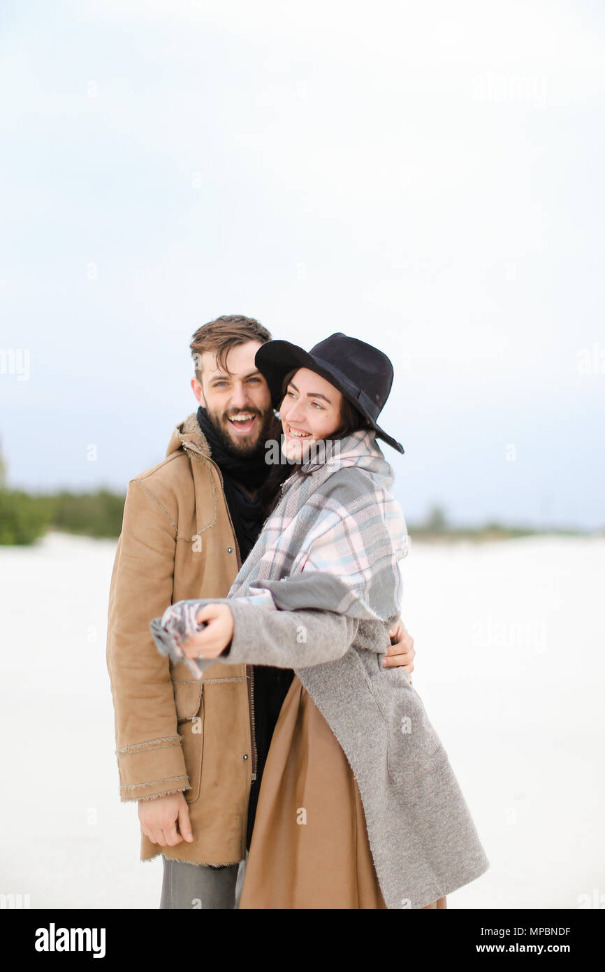 Feliz joven mujer y hombre abrigos bufandas de pie en el la nieve fondo Fotografía de stock - Alamy
