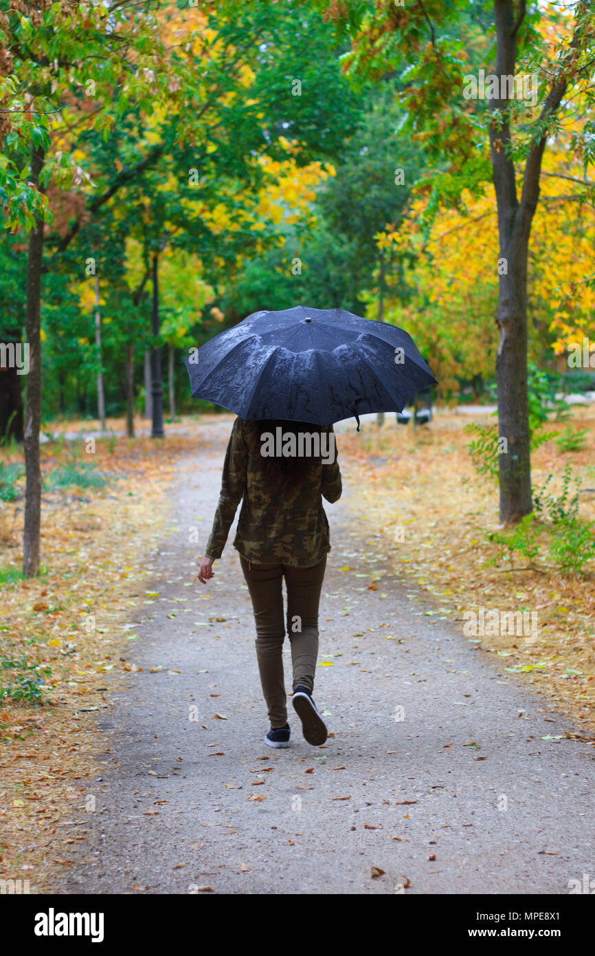 Mujer con paraguas de colores bajo la lluvia en el campo Stock Photo