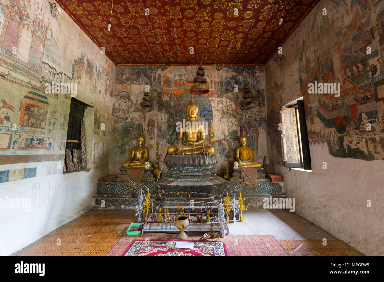Murales, altar y estatuas de Buda en el interior del templo de Wat Pa Huak en Luang Prabang, Laos. Foto de stock