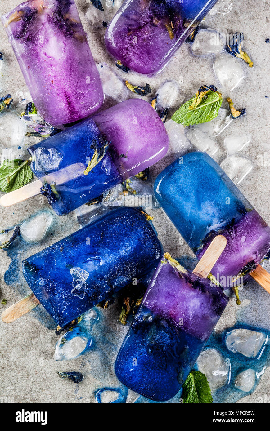 Naturalmente orgánico verano dulces caseros, azul y violeta paletas de  helado con mariposas de guisantes, té de flores de hormigón gris espacio  copia de fondo Fotografía de stock - Alamy