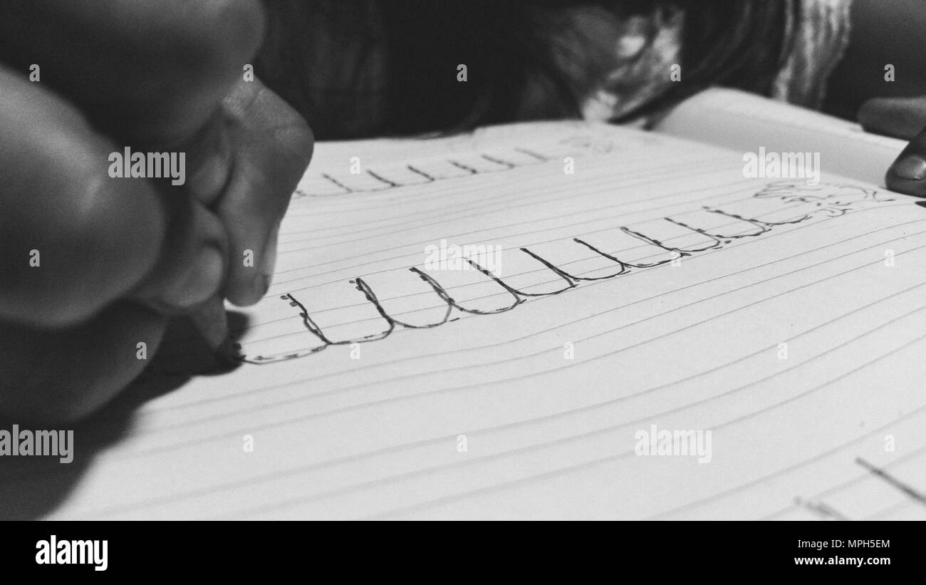 Cerca de manos de chica escrito en el bloc de notas colocadas en escritorios de madera Foto de stock