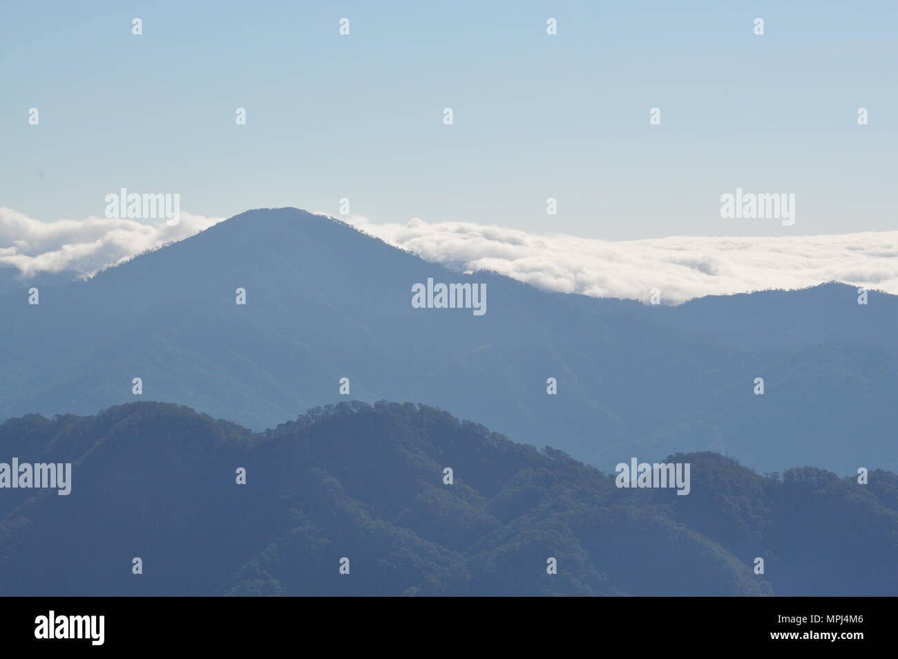 Nubes que cubren las crestas de las montañas de la Cordillera de campo durante las horas tempranas de la mañana visto desde el Monte Ulap durante nuestra caminata por el sendero ecológico. Foto de stock