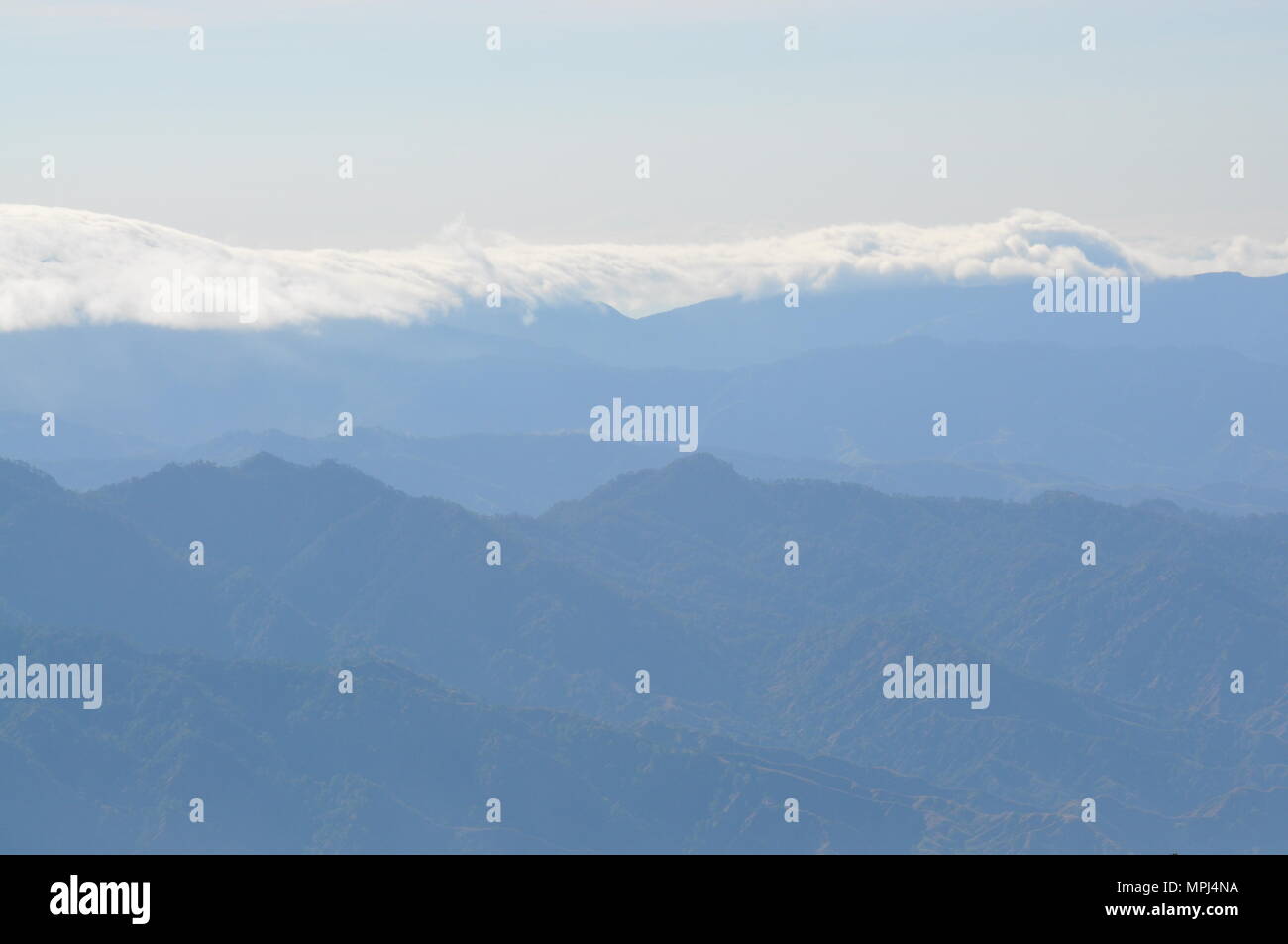 Nubes que cubren las crestas de las montañas de la Cordillera de campo durante las horas tempranas de la mañana visto desde el Monte Ulap durante nuestra caminata por el sendero ecológico. Foto de stock