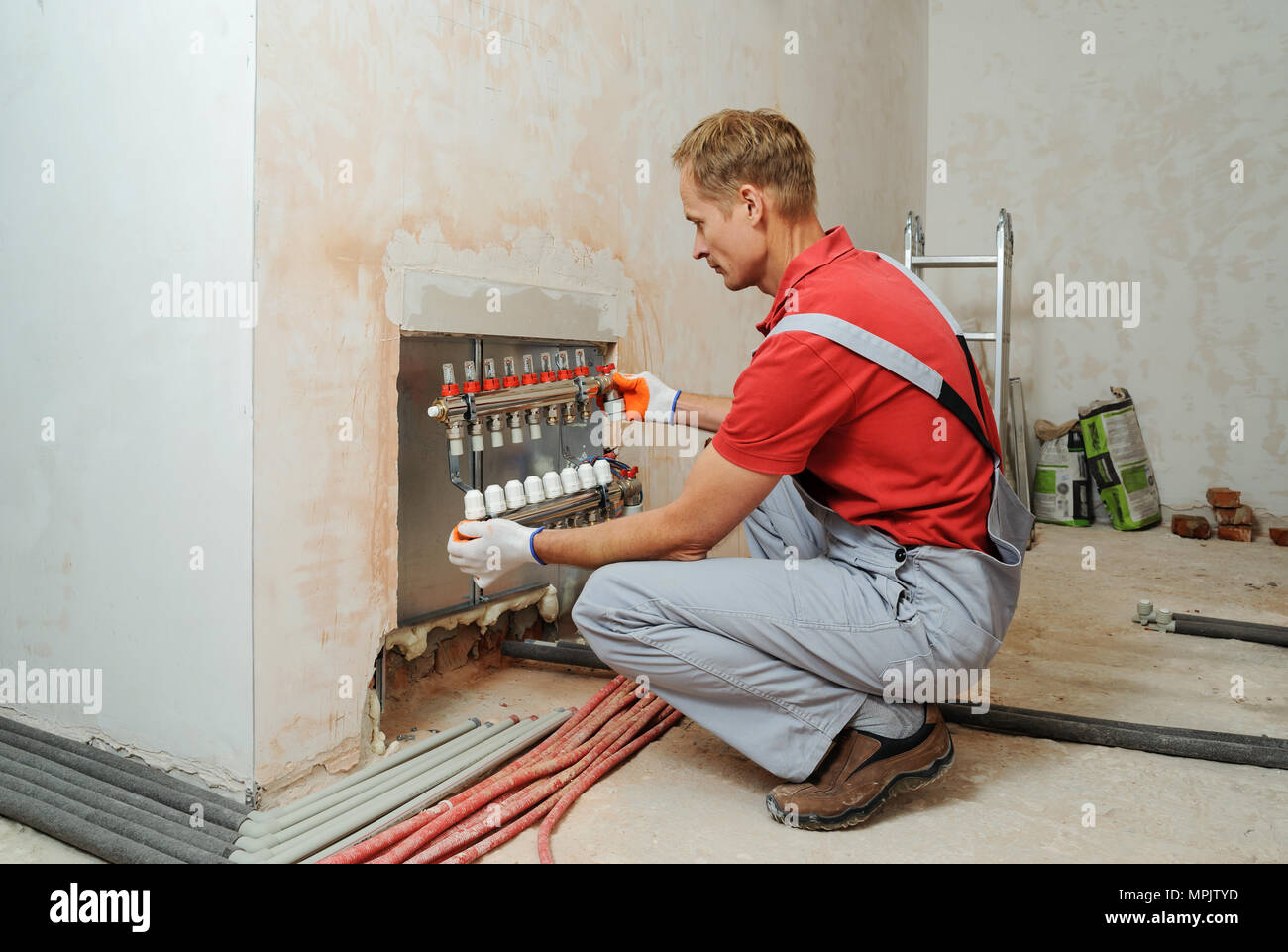 Trabajador profesional que instala el sistema eléctrico de calefacción por suelo  radiante en el interior Fotografía de stock - Alamy