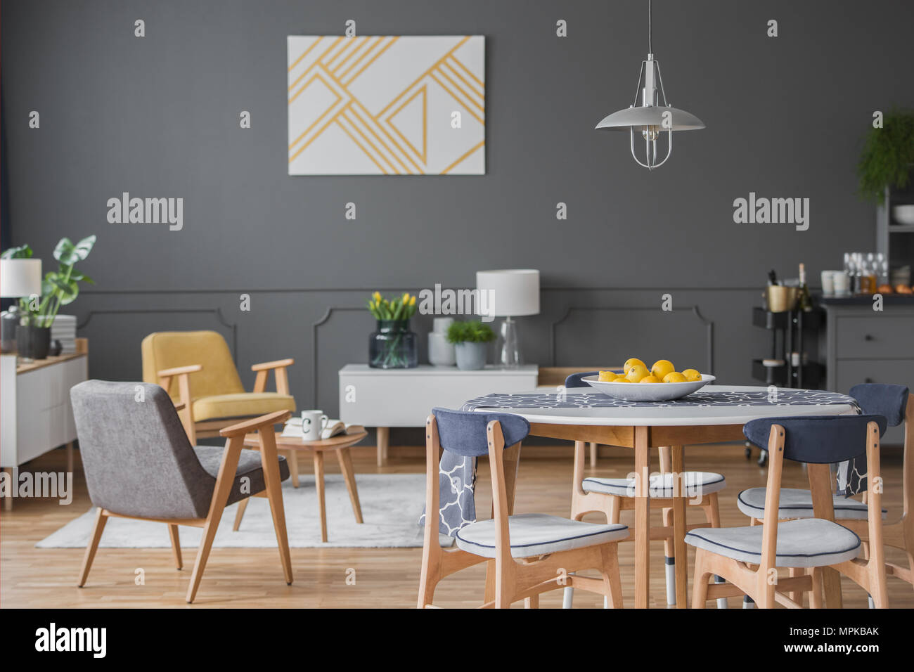 Sillas de madera en la mesa de comedor en gris salón interior con pintura  amarilla en una pared con moldura Fotografía de stock - Alamy