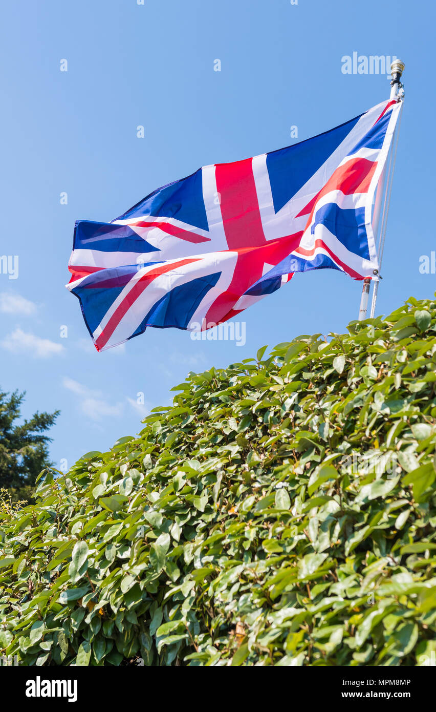 Union Jack bandera del Reino Unido de Gran Bretaña e Irlanda del Norte, volando sobre un poste en la parte delantera de una casa en Inglaterra, Reino Unido. Foto de stock