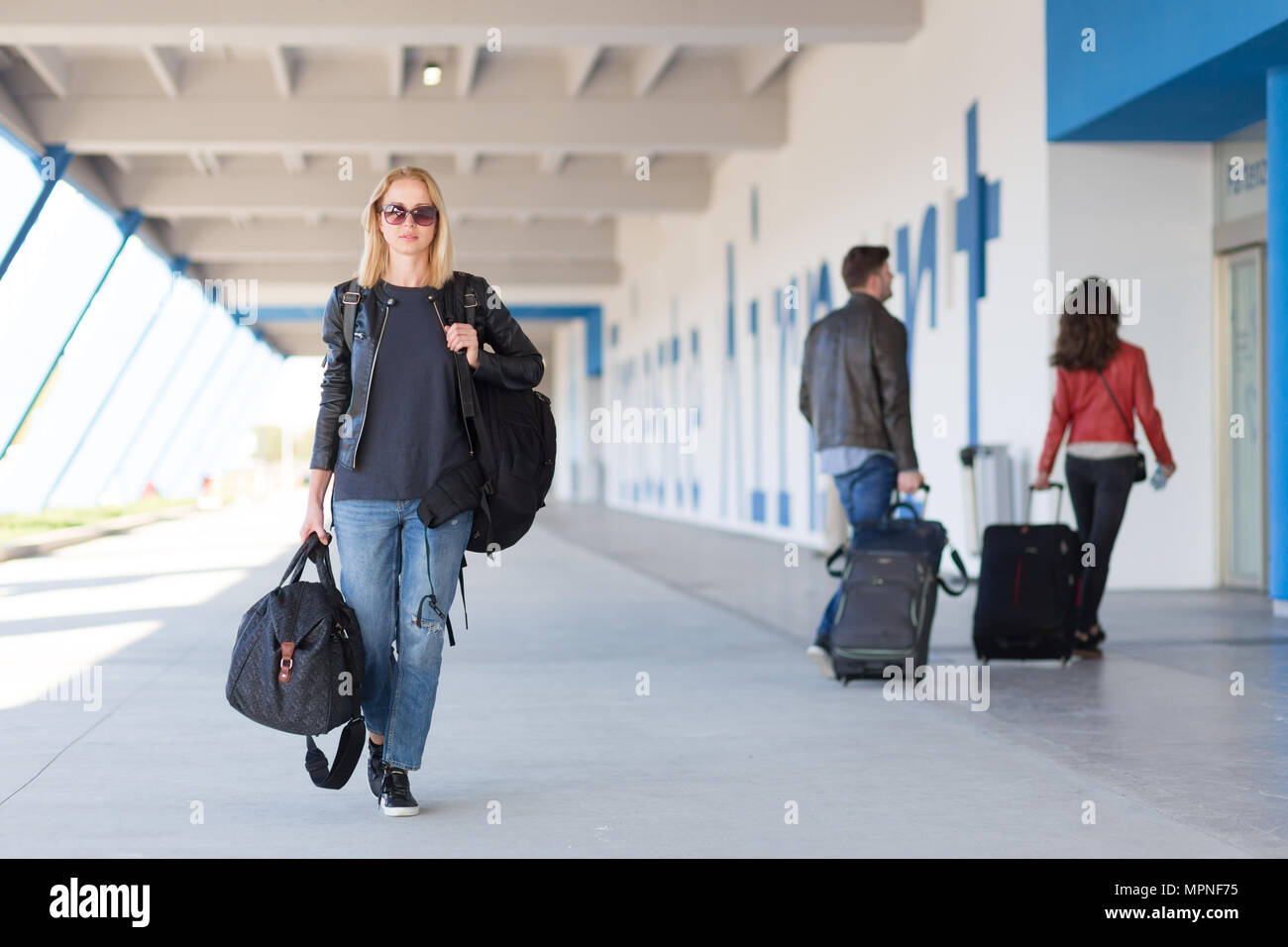 Retrato de joven mujer alegre viajero vistiendo ropa casual llevar mochila  pesada y el equipaje en el aeropuerto Fotografía de stock - Alamy