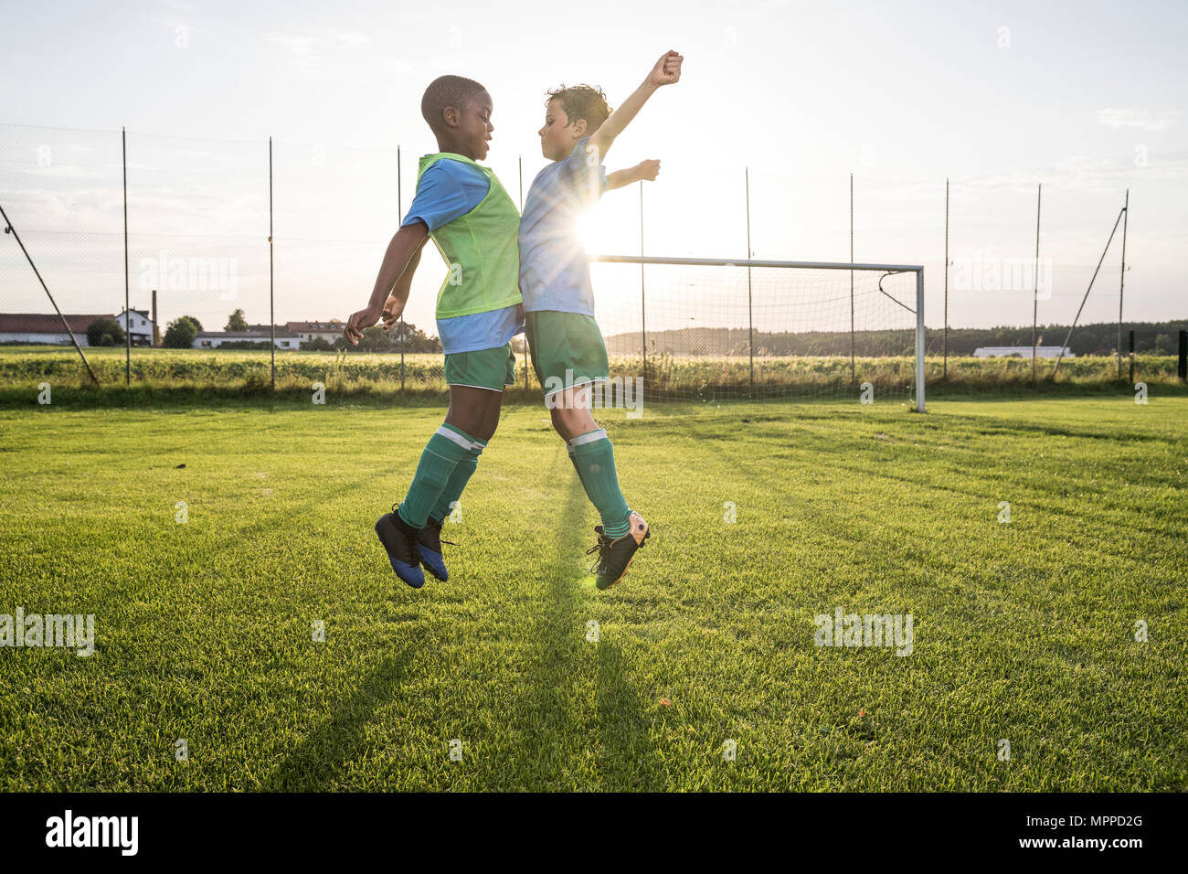 Los jóvenes futbolistas saltando sobre terreno de fútbol Foto de stock