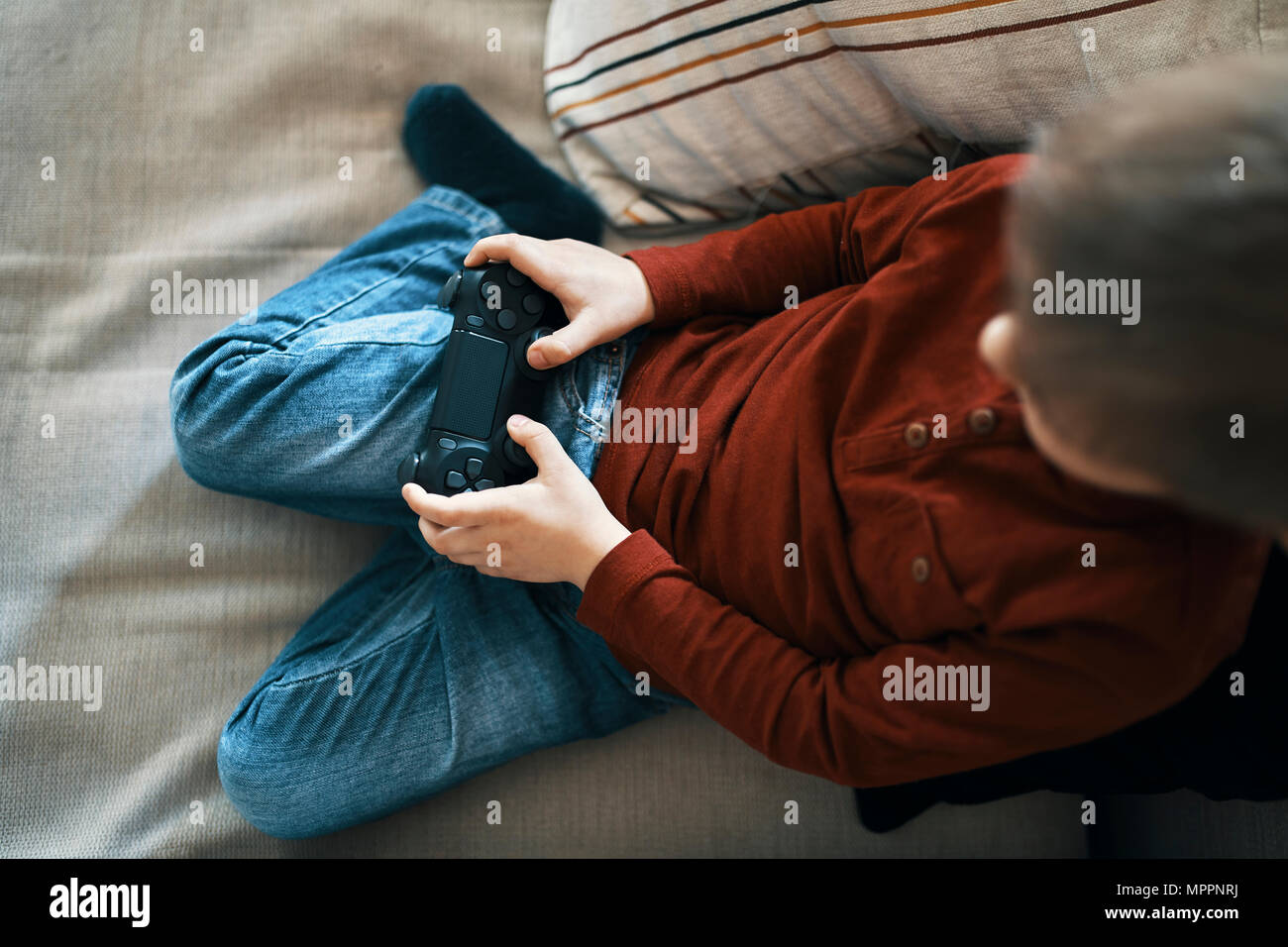 Chico sentado en el sofá jugando a juegos de ordenador, vista superior Foto de stock