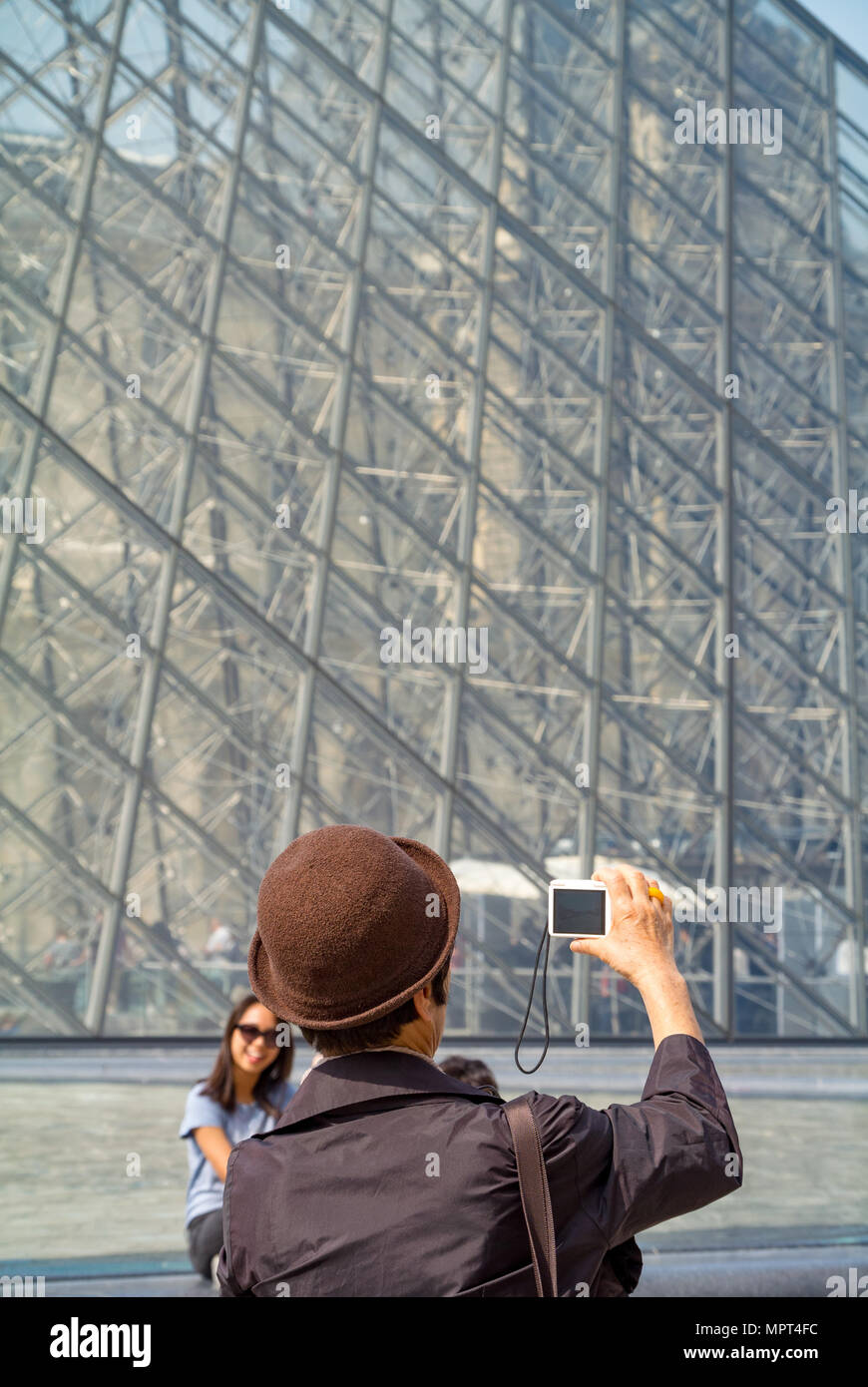 Una mujer asiática fotografiando una pirámide del Museo del Louvre, París, Francia Foto de stock