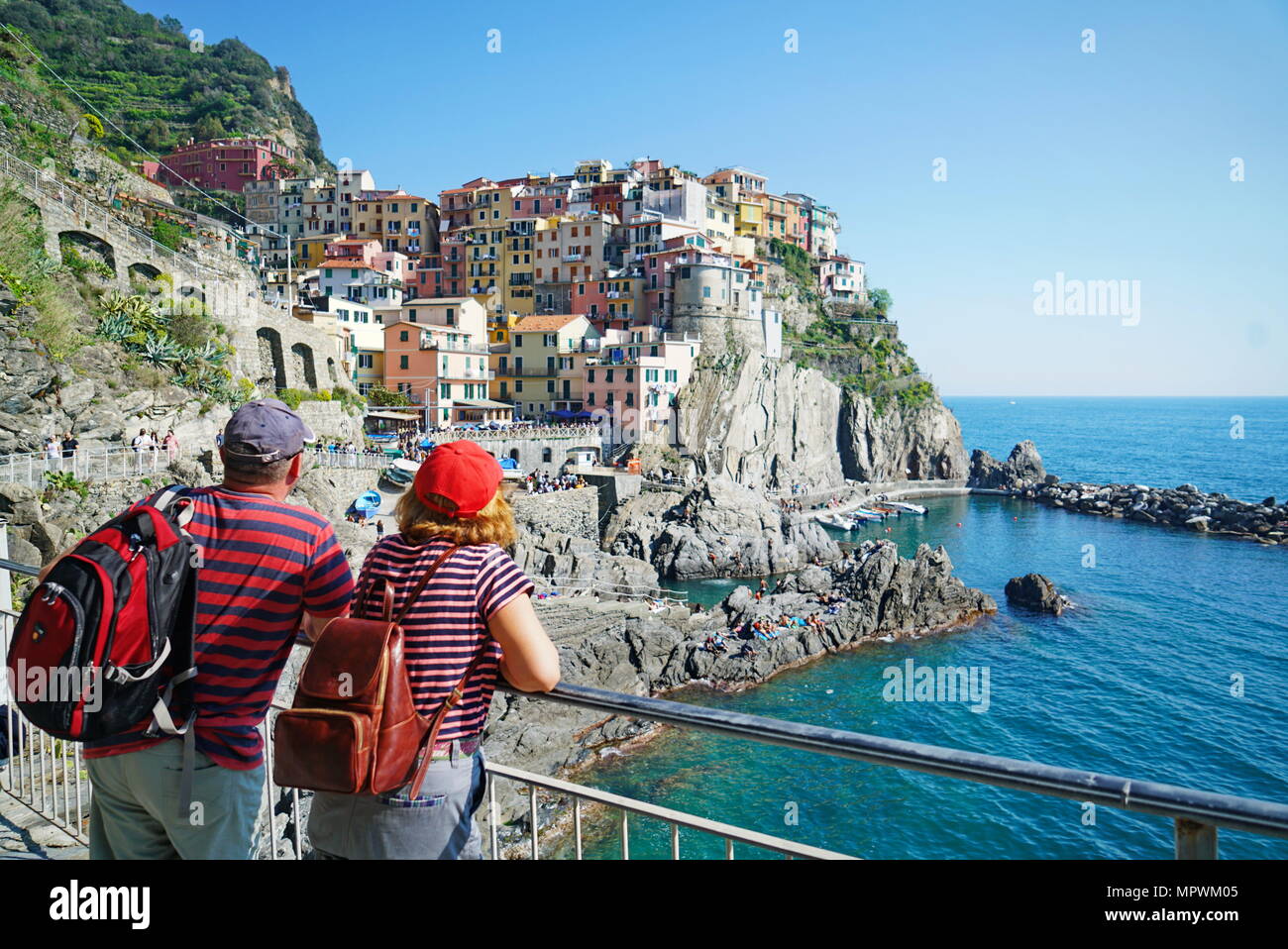 Una pareja de turistas admirar la hermosa vista de Manarola ciudad. Es uno de los cinco famosos coloridos pueblos del Parque Nacional Cinque Terre en Italia. Maná Foto de stock