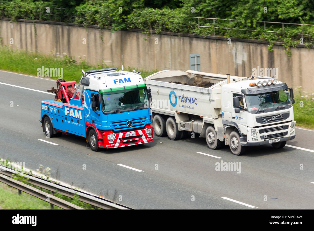 Vehículo comercial FAM desglose de recuperación pasando un camión Volvo FM410 marca de asfalto camión volquete en la autopista M61 cerca de Farnworth. Foto de stock