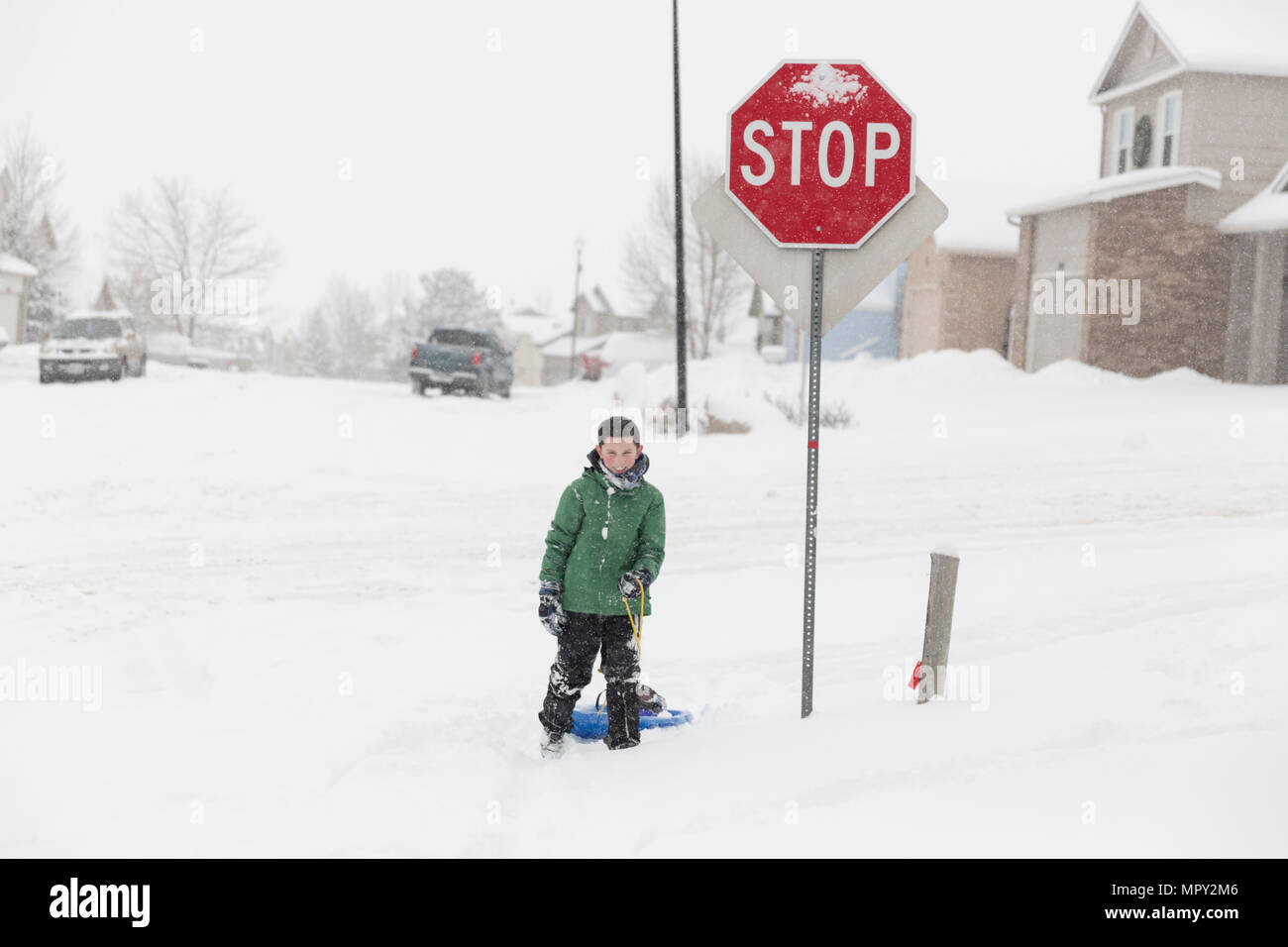 La longitud total del adolescente con carril de pie junto a la señal de pare en la carretera cubierta de nieve durante el invierno Foto de stock