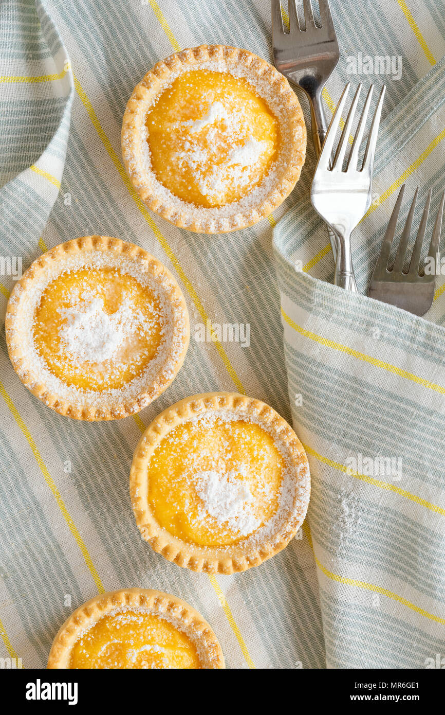 Tartaletas de limón con horquillas en una servilleta de franjas azules y amarillas. Foto de stock