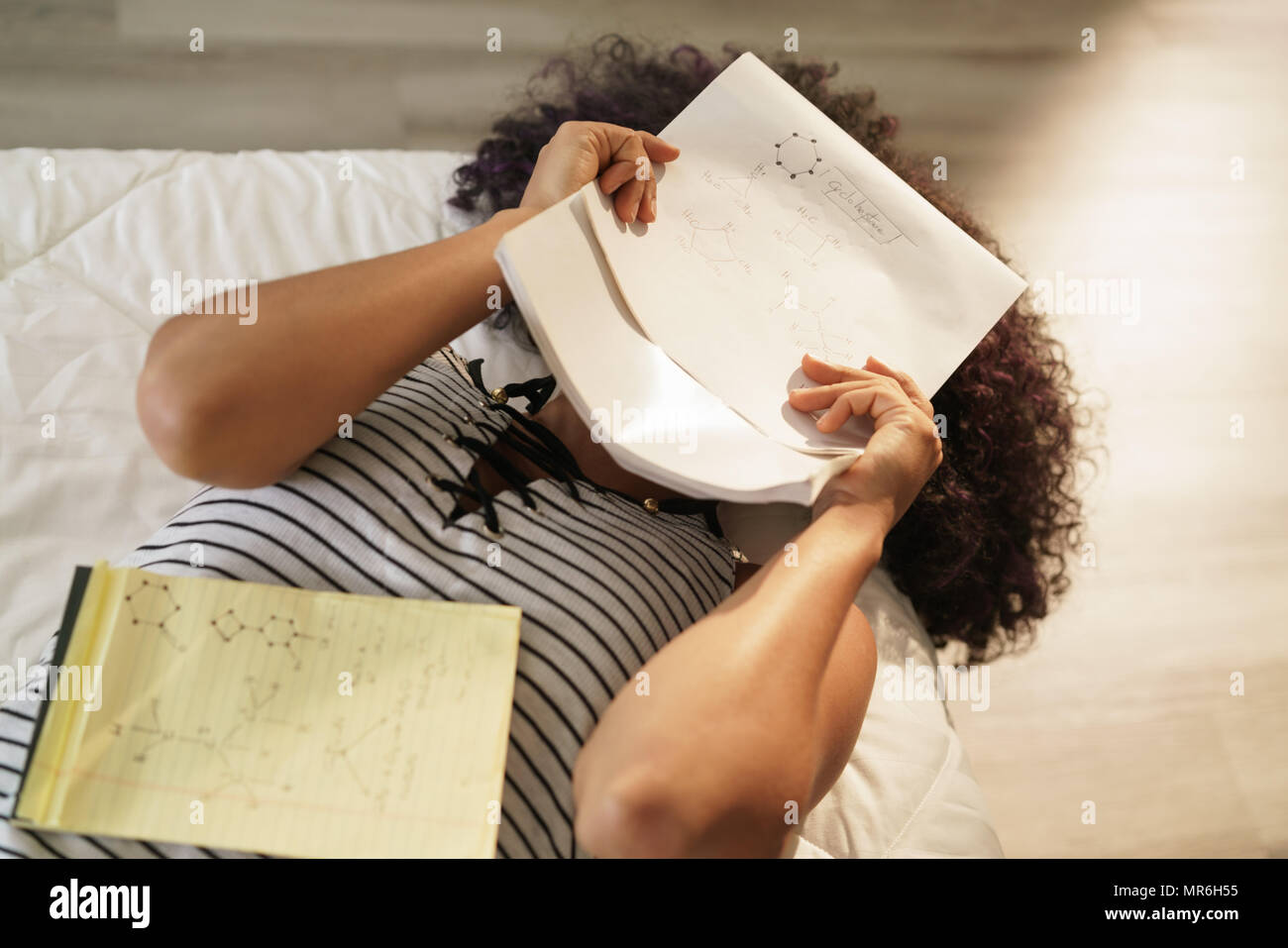 Estudiante universitario americano africano haciendo los deberes en la cama  en casa. Mujer Negra estudio química fórmulas, teniendo problemas para  memorizar notas sobre el ejercicio Fotografía de stock - Alamy