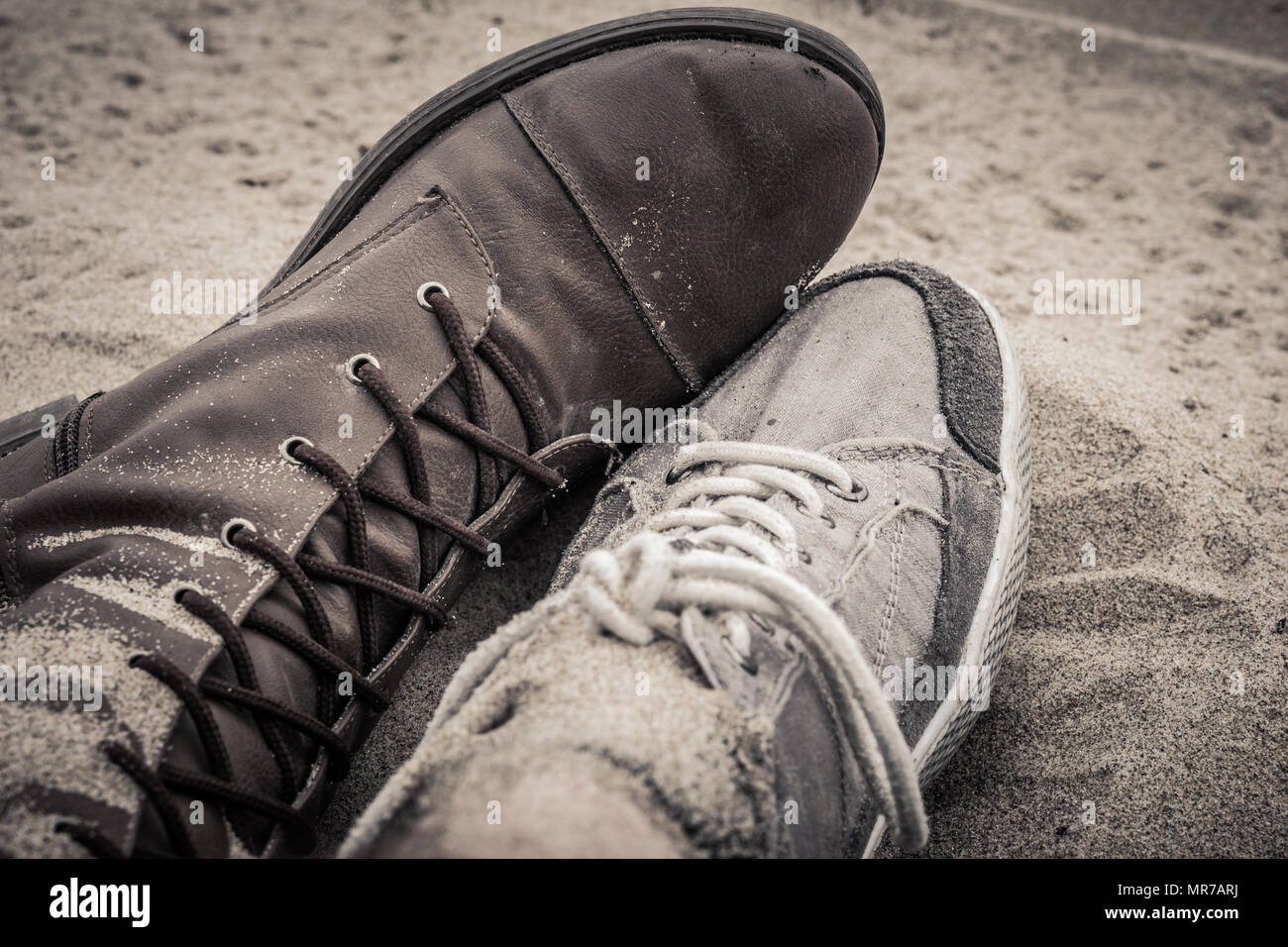 Zapatos de hombre y mujer tumbados uno junto al otro en la arena. Colores  Sepia Fotografía de stock - Alamy