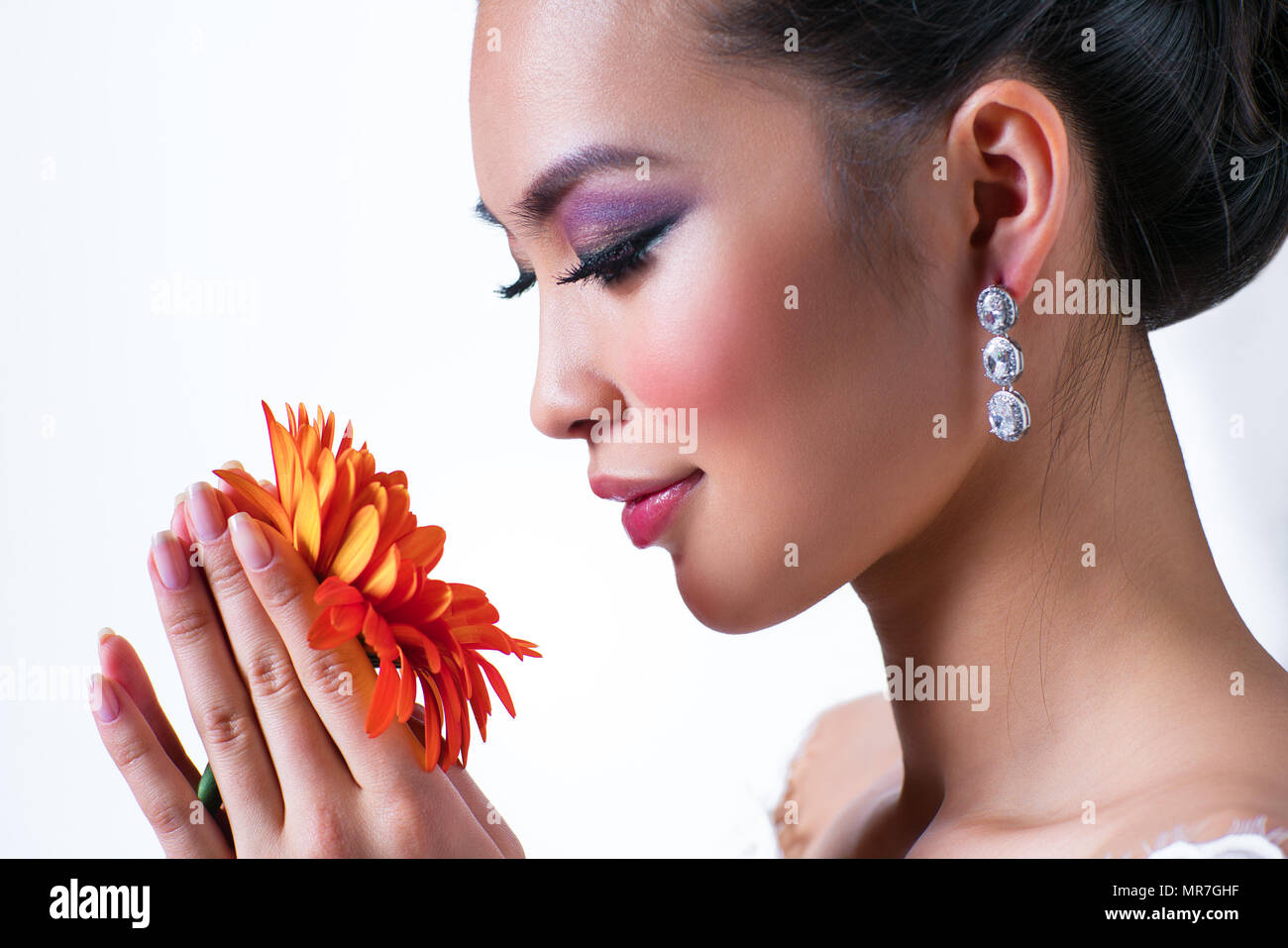 Joven mujer asiática con flor retrato sobre fondo blanco. Foto de stock